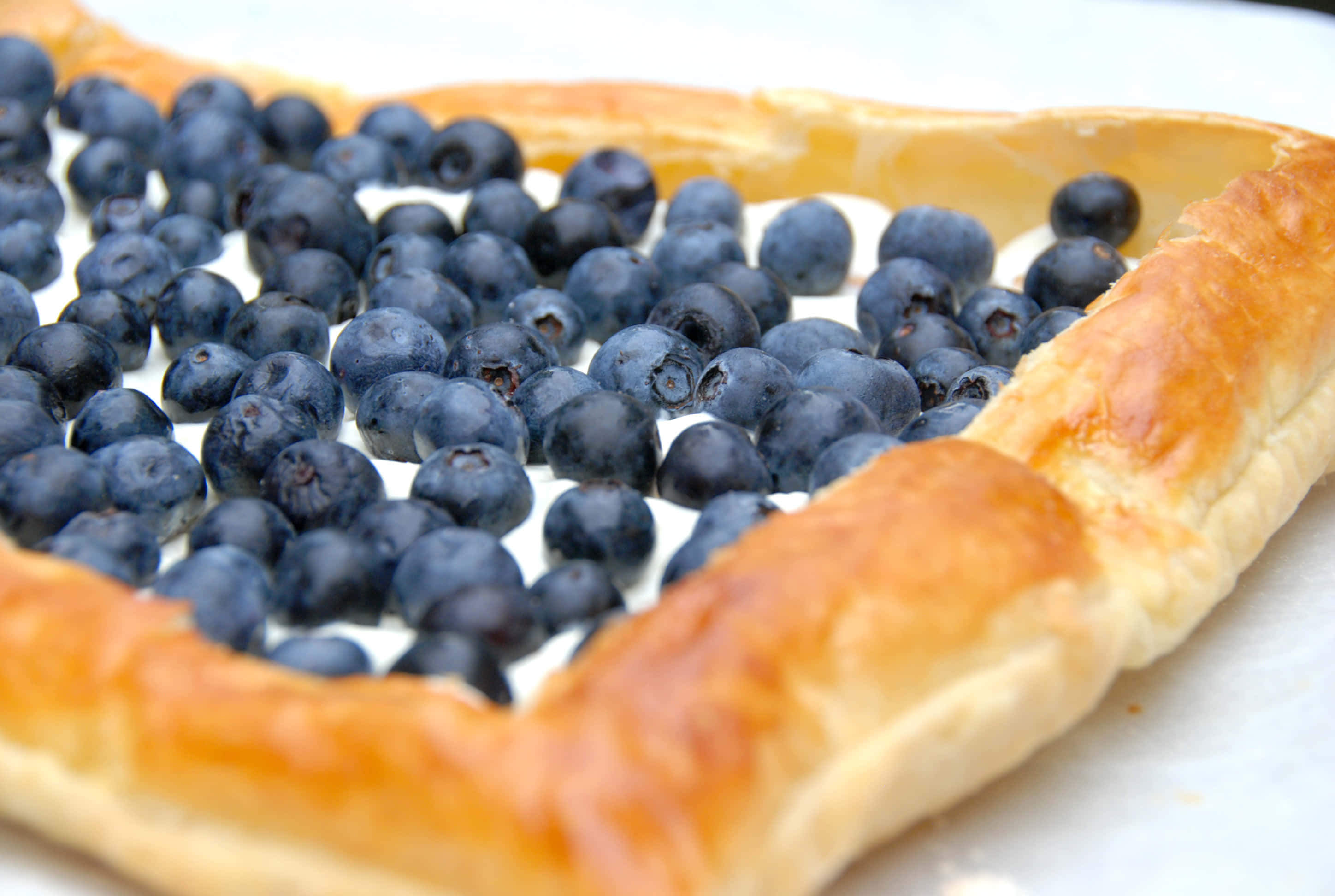 Blueberries Tart 桌布 壁紙 — 一個金黃色酥皮撻的近鏡，裡面裝滿了飽滿的藍莓，排列成心形。