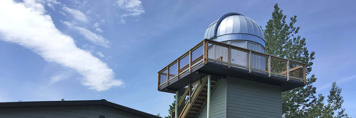 Observatory 桌布 壁紙 — 一個銀色圓頂天文台坐落在木製甲板上，背景是晴朗的藍天和零星的白雲。
