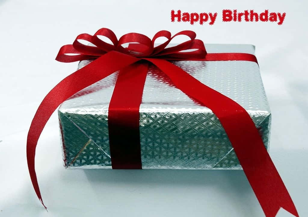 Birthday Wishes 桌布 壁紙 — 一個銀色禮物盒，上面有紅色絲帶蝴蝶結，上方有紅色 'Happy Birthday' 文字。
