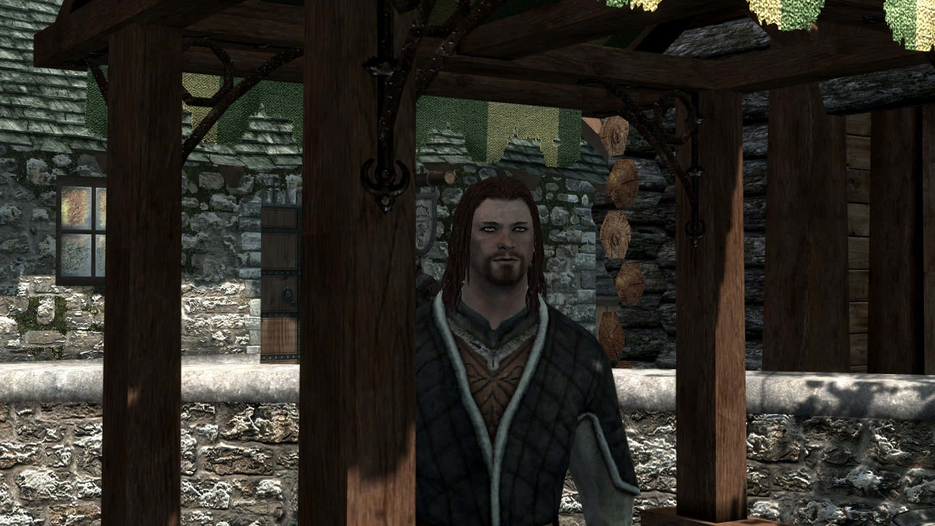 Skyrim Brynjolf 桌布 壁紙 — 一個長髮男人站在一個掛著燈籠的質樸石村嘅木製涼亭下。