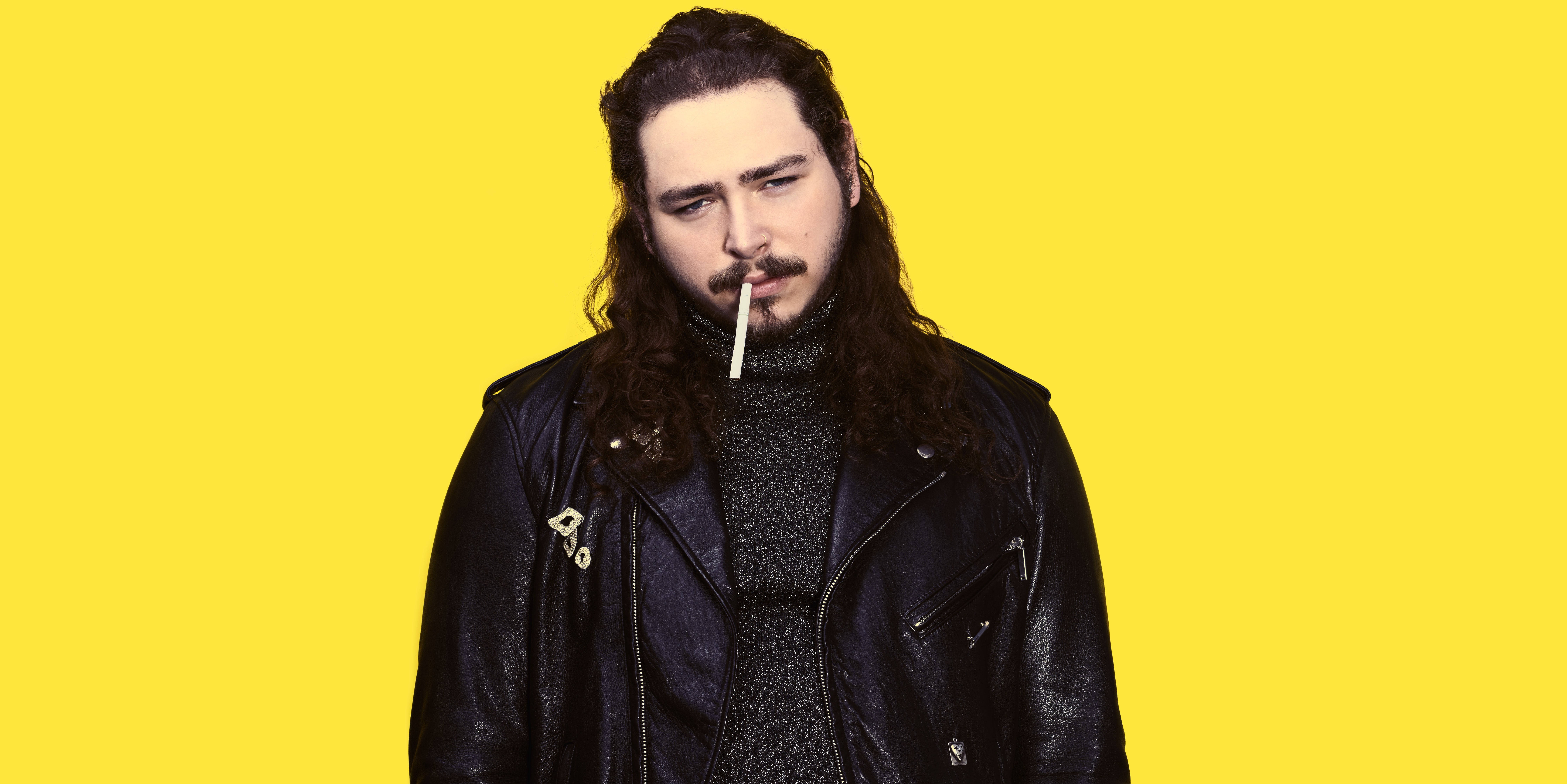 Post Malone Beerbongs Portrait 壁紙 — 一個長黑髮、留鬍子的男人，穿著黑色皮夾克，嘴裡叼著香煙，背景是明亮的黃色。