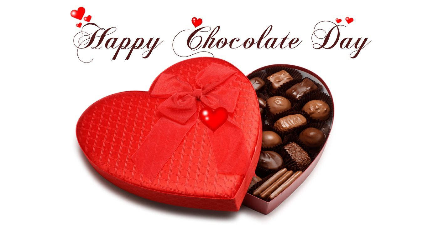 Chocolate Day 桌布 壁紙 — 一個閃亮的紅色心形朱古力盒，飾有蝴蝶結和小心形，打開後露出各種朱古力，背景為白色。