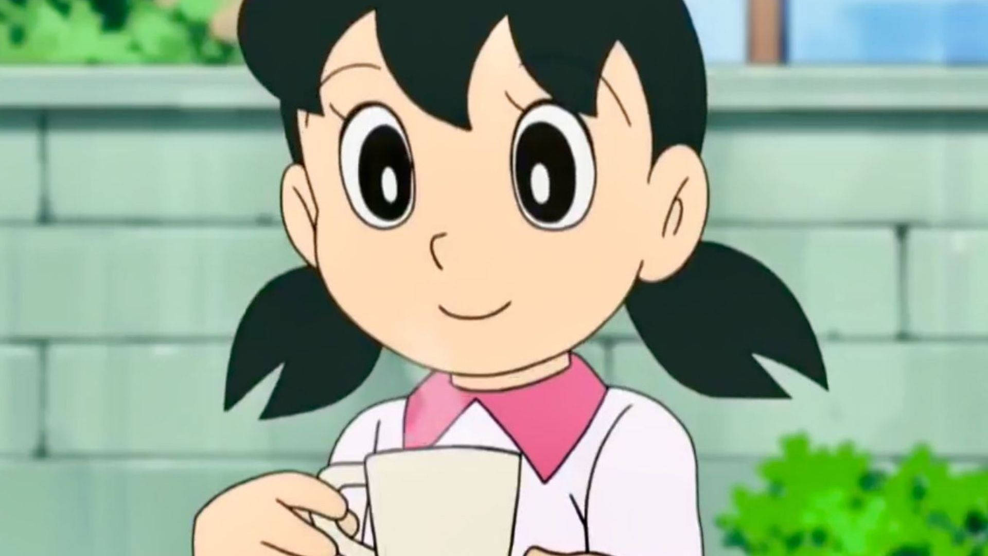 Doraemon 桌布 壁紙 — 一個開心的動漫女孩，黑色雙馬尾，拿著白色馬克杯，背景是綠色磚牆。
