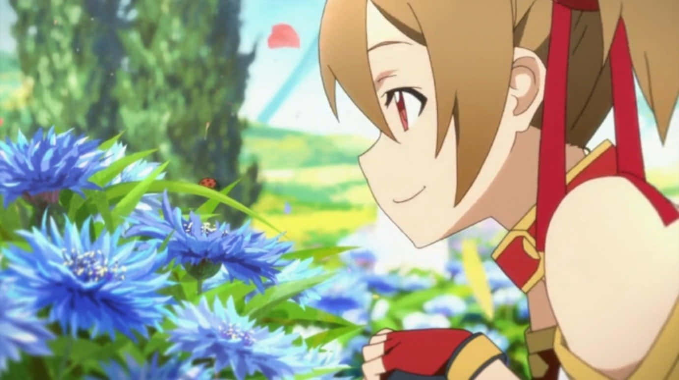 Sword Art Online Silica 桌布 壁紙 — 一個開朗的動漫女孩，棕色頭髮和紅色眼睛，在陽光明媚的草地上微笑著輕輕觸摸鮮豔的藍色矢車菊。