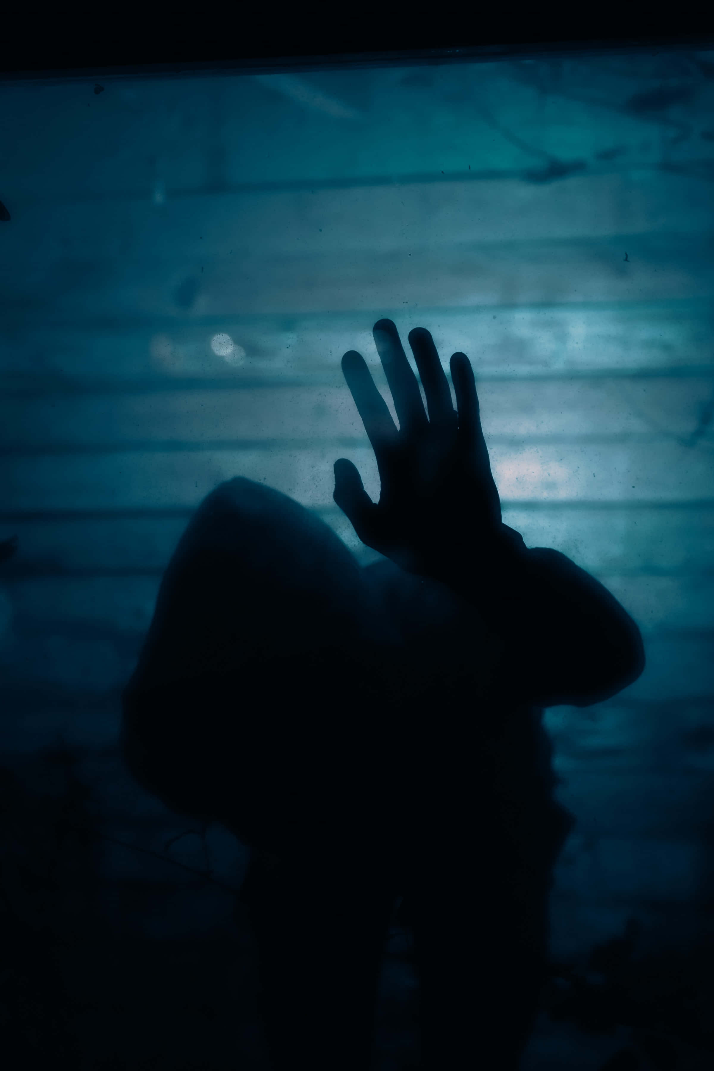 Mysterious 桌布 壁紙 — 一個陰暗的身影將手按在沐浴在冷藍光線中的紋理玻璃板上。