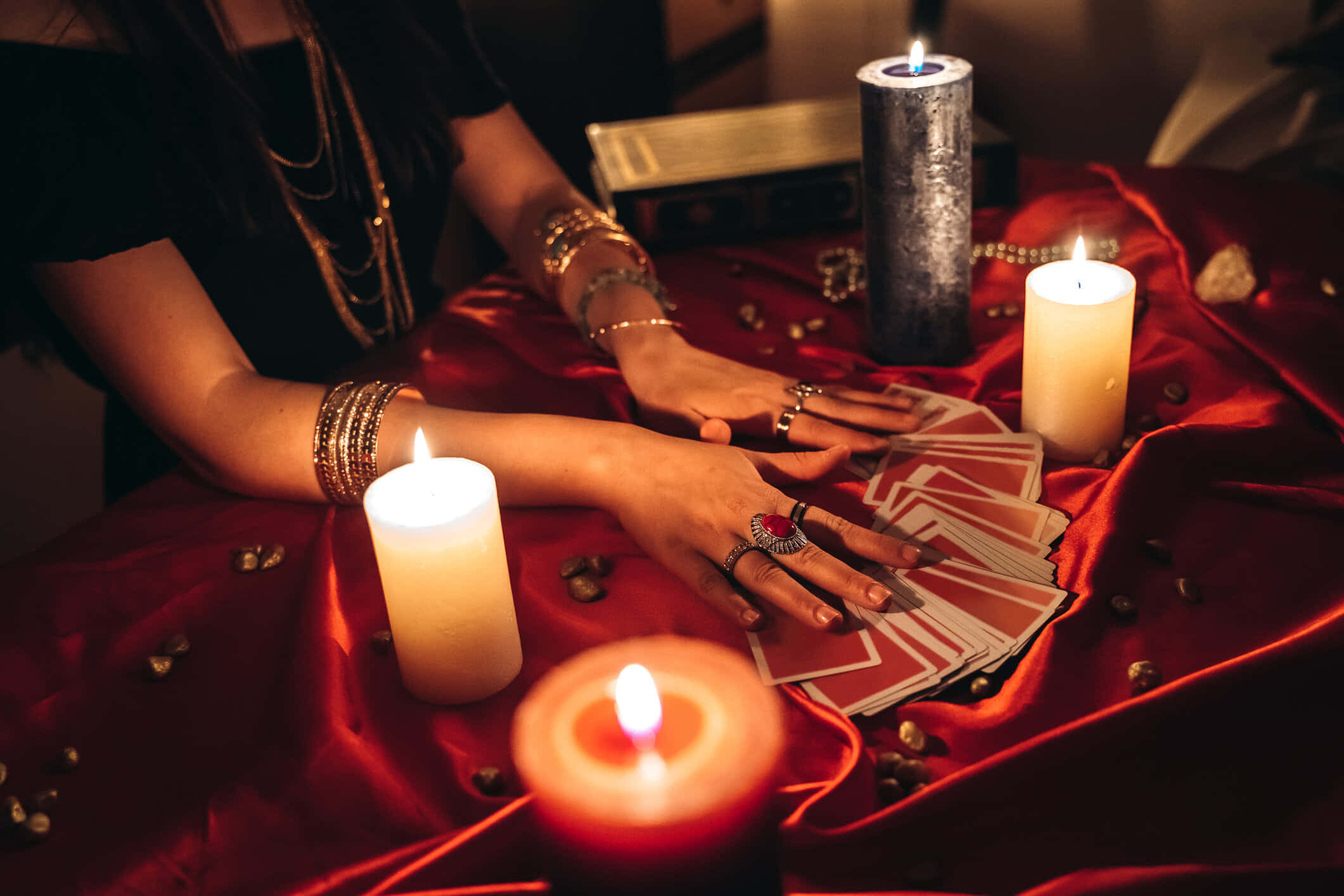 Fortune Teller 桌布 壁紙 — 一個雙手裝飾的人正在一張華麗的紅色天鵝絨布上攤開塔羅牌，布面被閃爍的蠟燭和散落的水晶照亮。