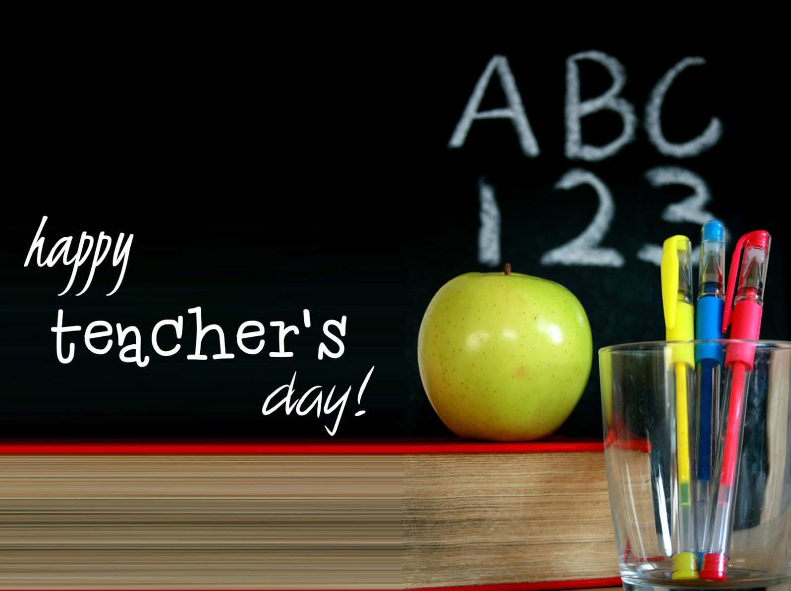Happy Teachers Day 桌布 壁紙 — 一個青蘋果和彩色筆放在一本書上，前面是黑板，上面寫著ABC 123和happy teacher's day。