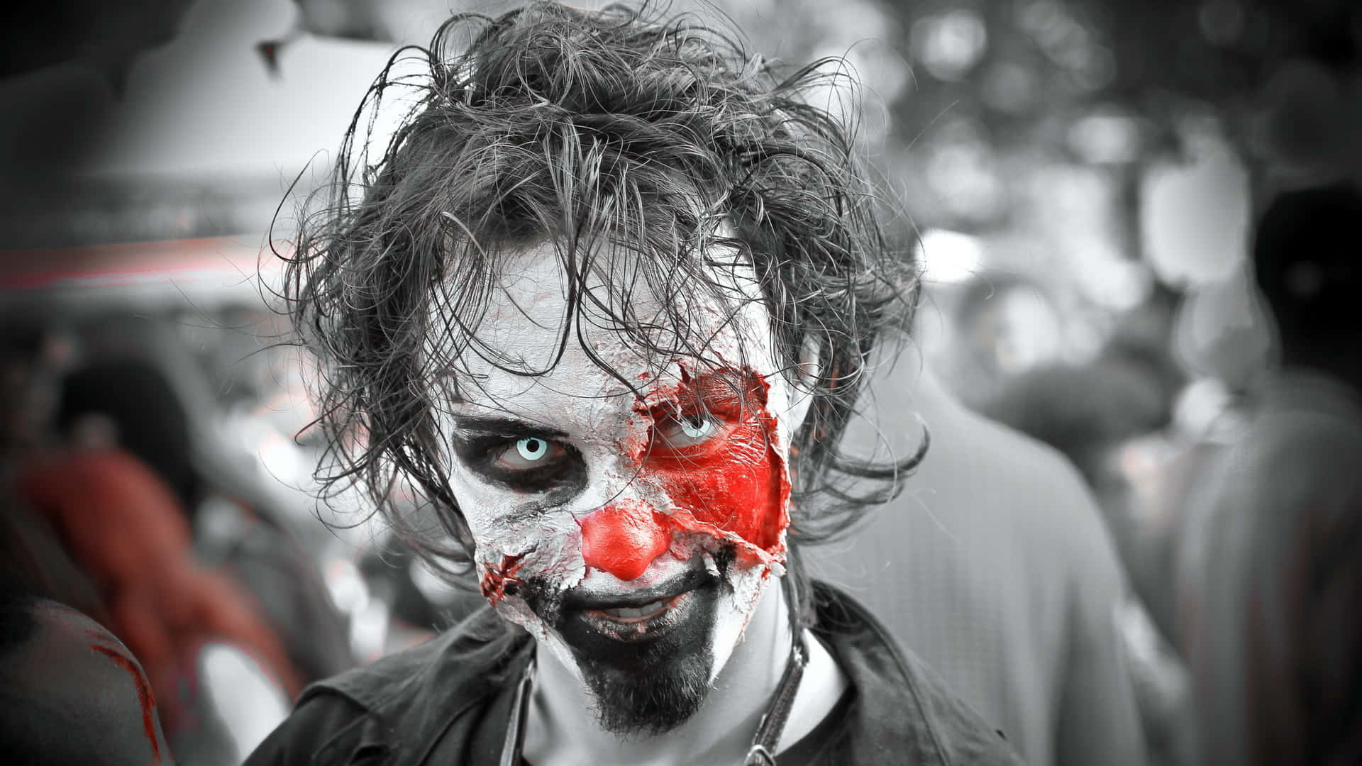 Zombie Costumes 桌布 壁紙 — 一個頭髮凌亂、半張臉塗成小丑、帶有血跡和撕裂化妝的人，強烈地凝視著相機。