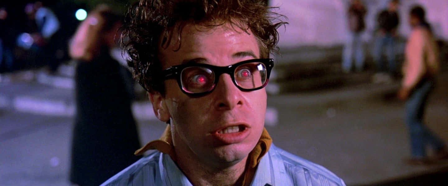 rick moranis 桌布 壁紙 — 一個頭髮凌亂、眼睛發出紅光的男人在夜晚的霓虹燈下震驚地凝視。