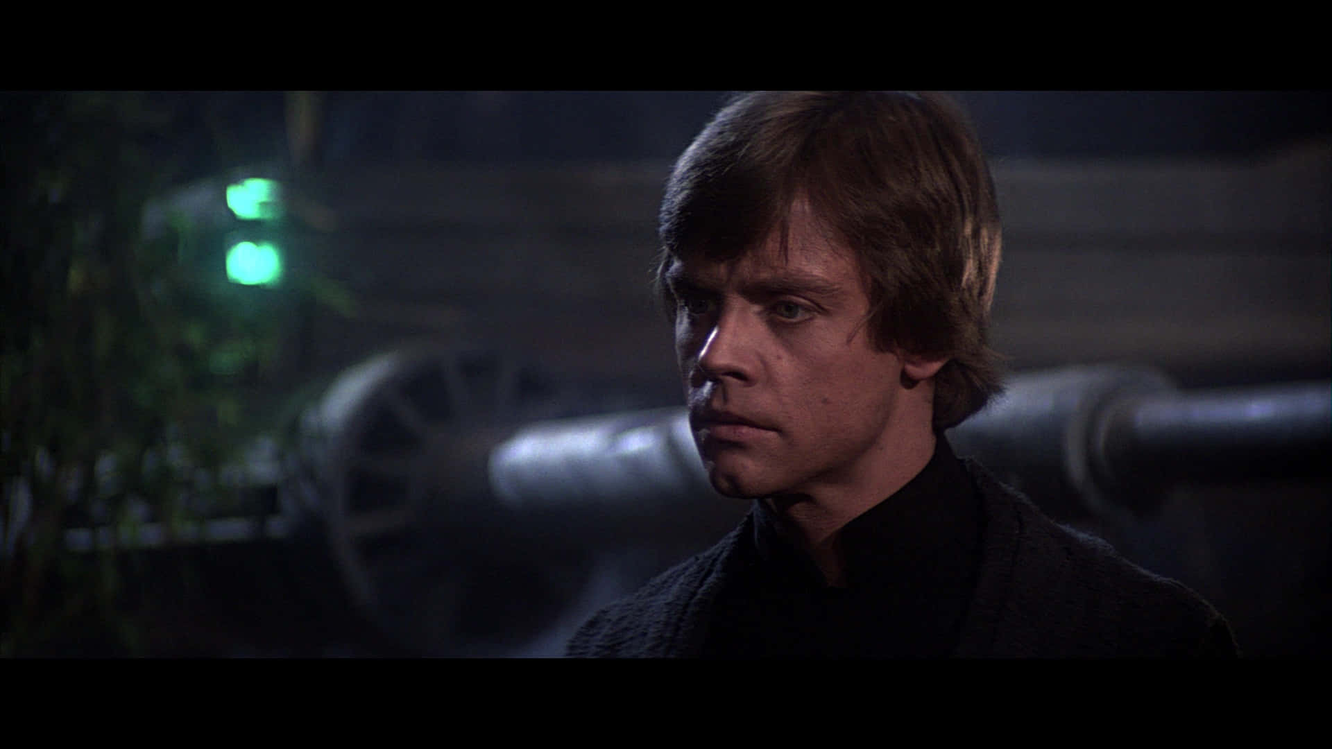 Return Of The Jedi 桌布 壁紙 — 一個頭髮凌亂的年輕男子在昏暗的場景中凝視著，身後有發光的綠色燈光和模糊的機器。