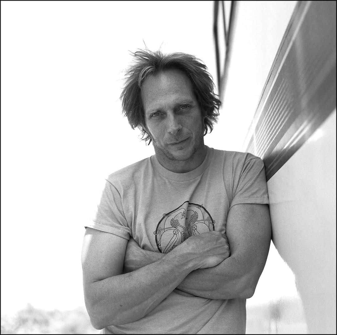 William Fichtner 桌布 壁紙 — 一個頭髮凌亂的男人靠著條紋牆壁，雙臂交叉，呈現出鮮明的黑白肖像。