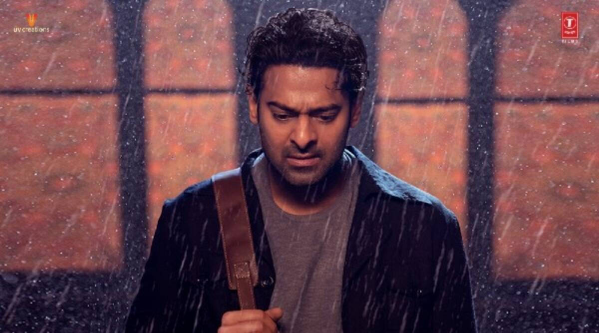 Prabhas 桌布 壁紙 — 一個頭髮濕透的男人在傾盆大雨中站著，手持結他帶，背景是暖色調的窗戶。