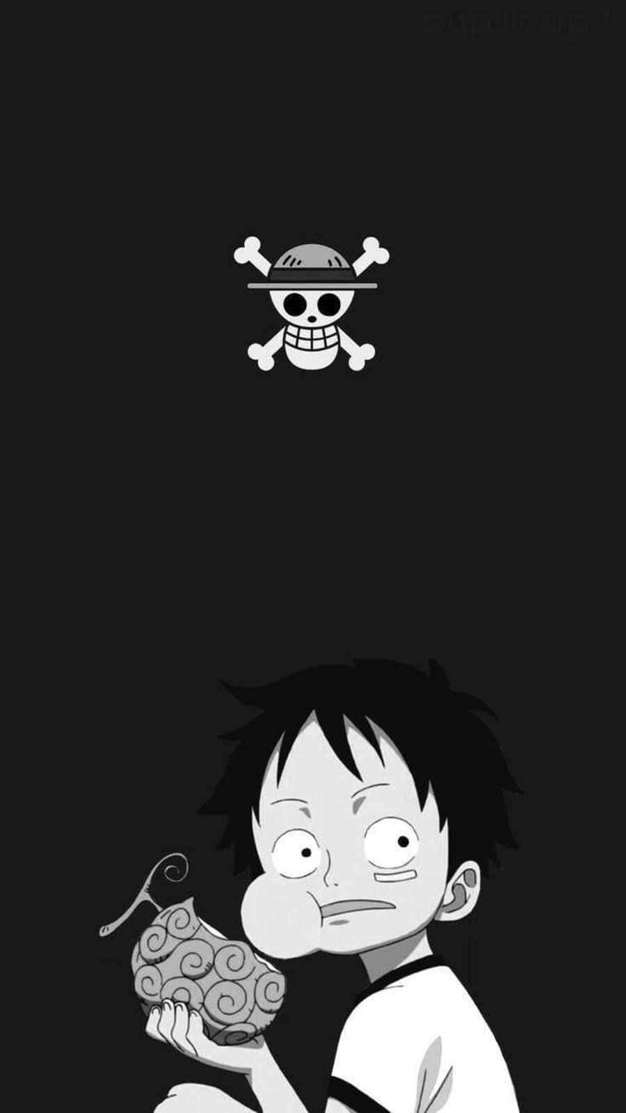 One Piece Manga 桌布 壁紙 — 一個頭髮豎起的年輕男孩拿著一個有圖案的水果，一個骷髏頭和交叉骨標誌漂浮在他上方，背景是深色的。