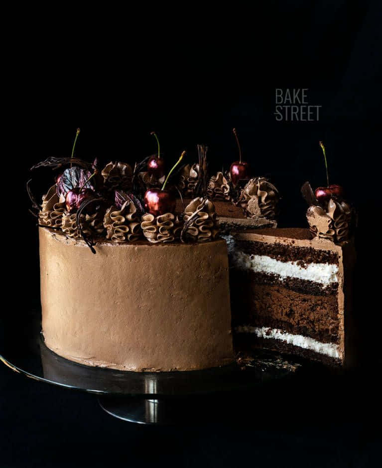 Black Forest Cake 桌布 壁紙 — 一個頹廢的巧克力蛋糕，上面有光澤的櫻桃和裱花糖霜，放在黑色架子上，背景深色。