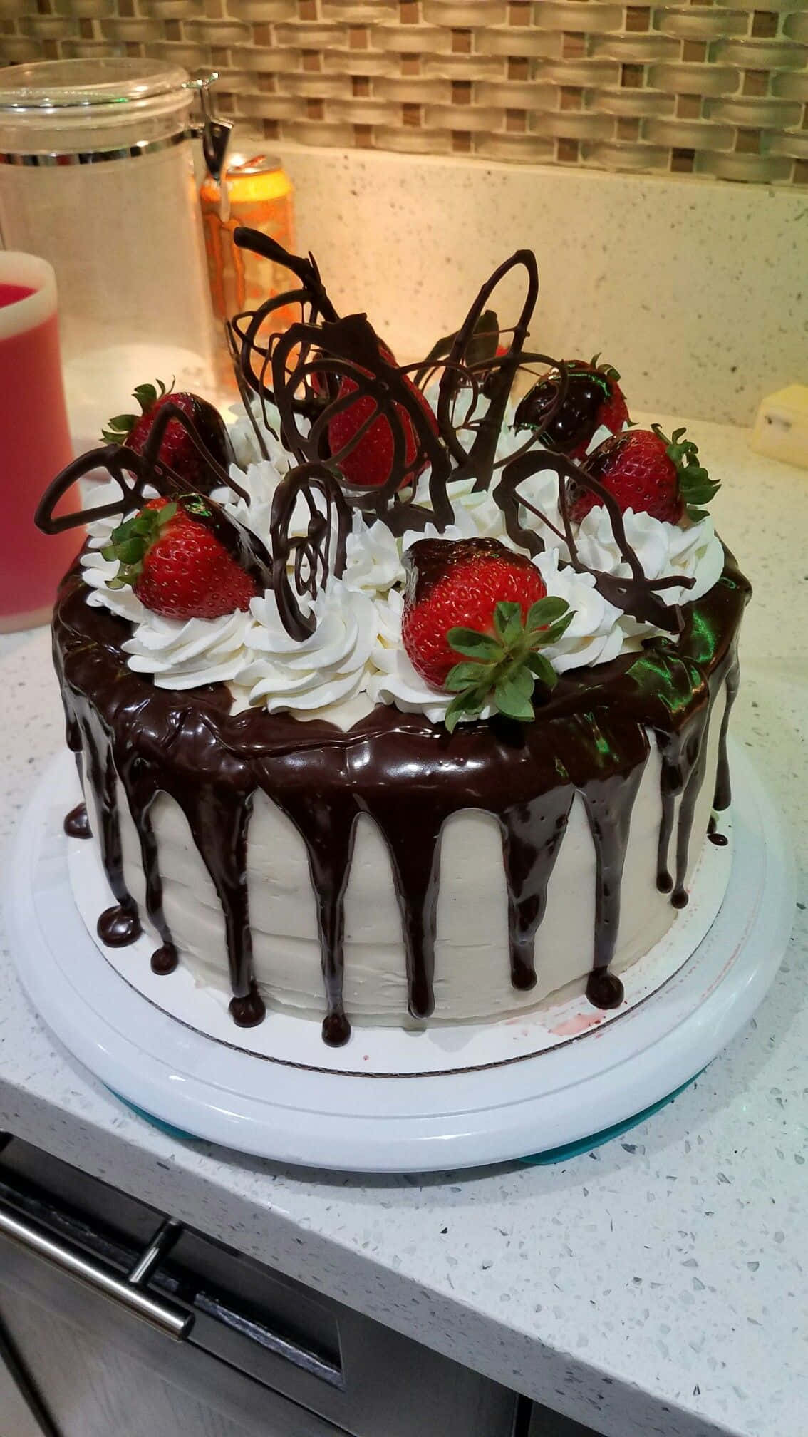 Black Forest Cake 桌布 壁紙 — 一個頹廢的朱古力滴落蛋糕，上面鋪滿新鮮草莓和忌廉，放在廚房枱面上。