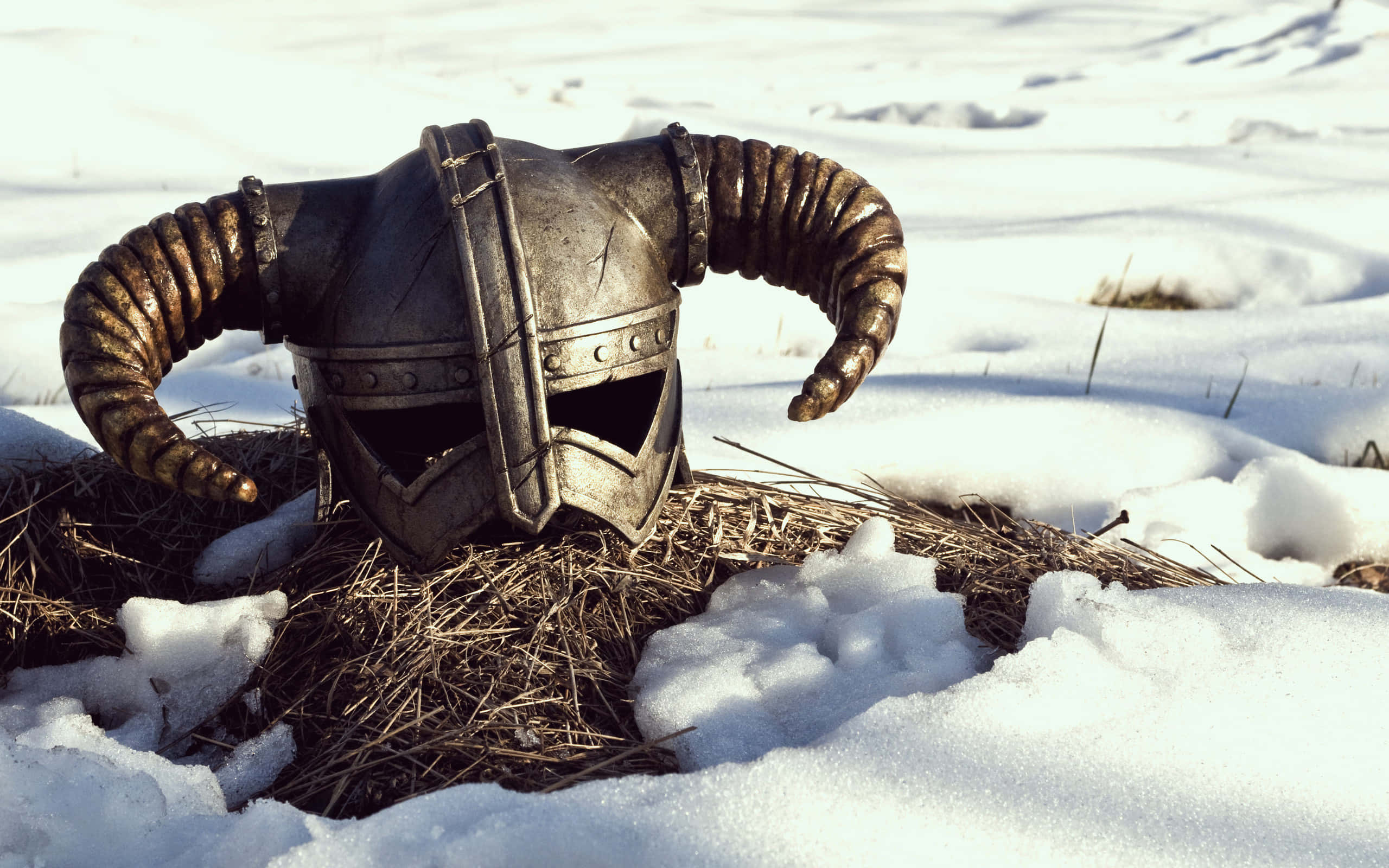 dovahkiin 桌布 壁紙 — 一個風化嘅有角頭盔喺陽光普照下，放喺雪地嘅乾草捆上面。