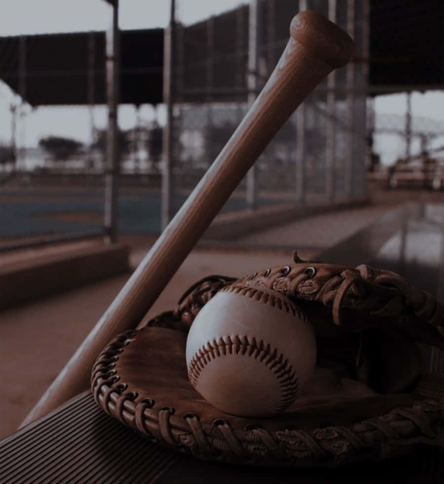 Cool Baseball 桌布 壁紙 — 一個風化的棒球棍傾斜喺一個皮手套上面，手套托住一個用過嘅棒球，喺一個塵土飛揚嘅球場嘅長凳上。