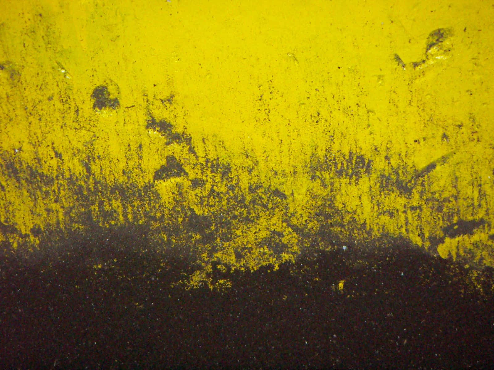 Yellow Abstract 桌布 壁紙 — 一個風化的黃色表面，帶有深色污垢和紋理，逐漸過渡到深黑色的下半部分。