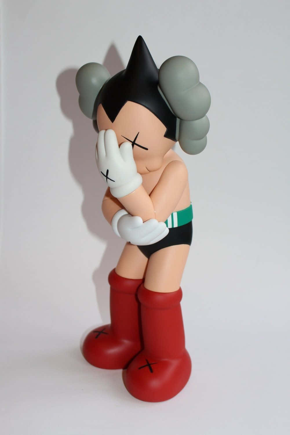 Kaws Astro Boy 桌布 壁紙 — 一個風格化的Astro Boy公仔，X形眼睛，雙手遮臉，背景為純白色。