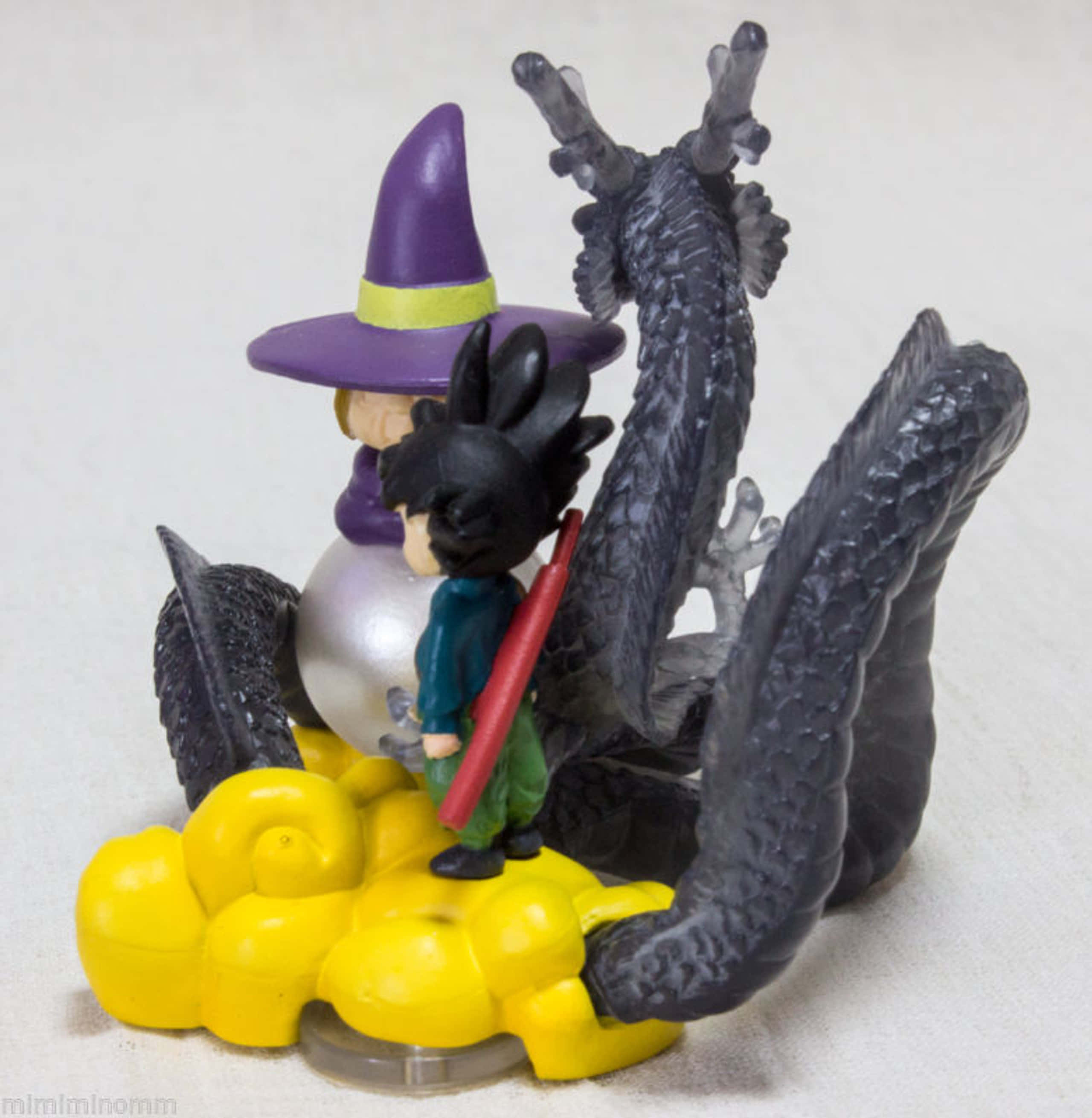 Baba Yaga 桌布 壁紙 — 一個風格化的動漫公仔，描繪女巫和小孩騎著黑龍在明亮的黃色雲朵上。
