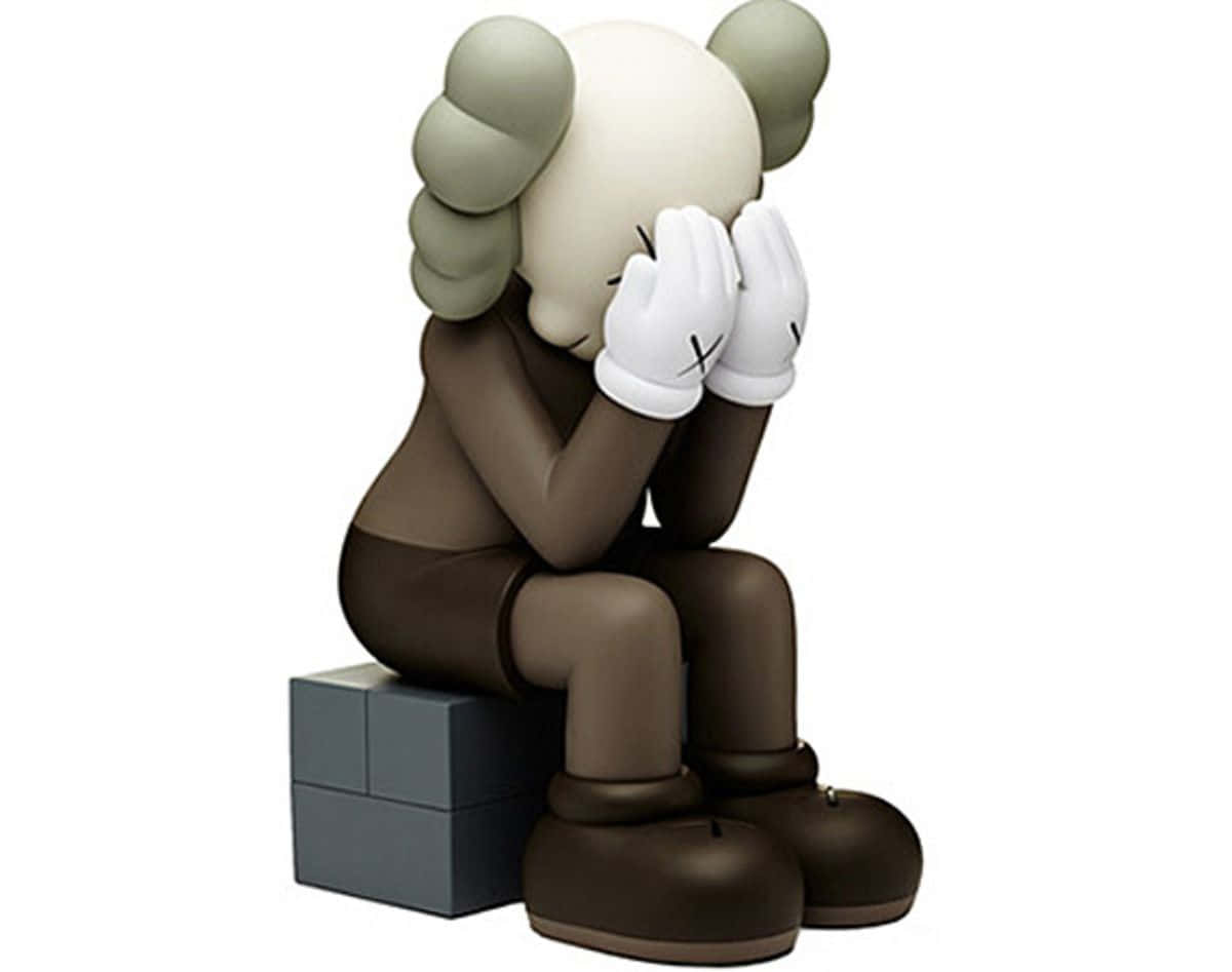 Kaws Astro Boy 桌布 壁紙 — 一個風格化的棕色人物，綠色頭髮，坐在灰色方塊上，用戴著白色手套的手遮住臉。