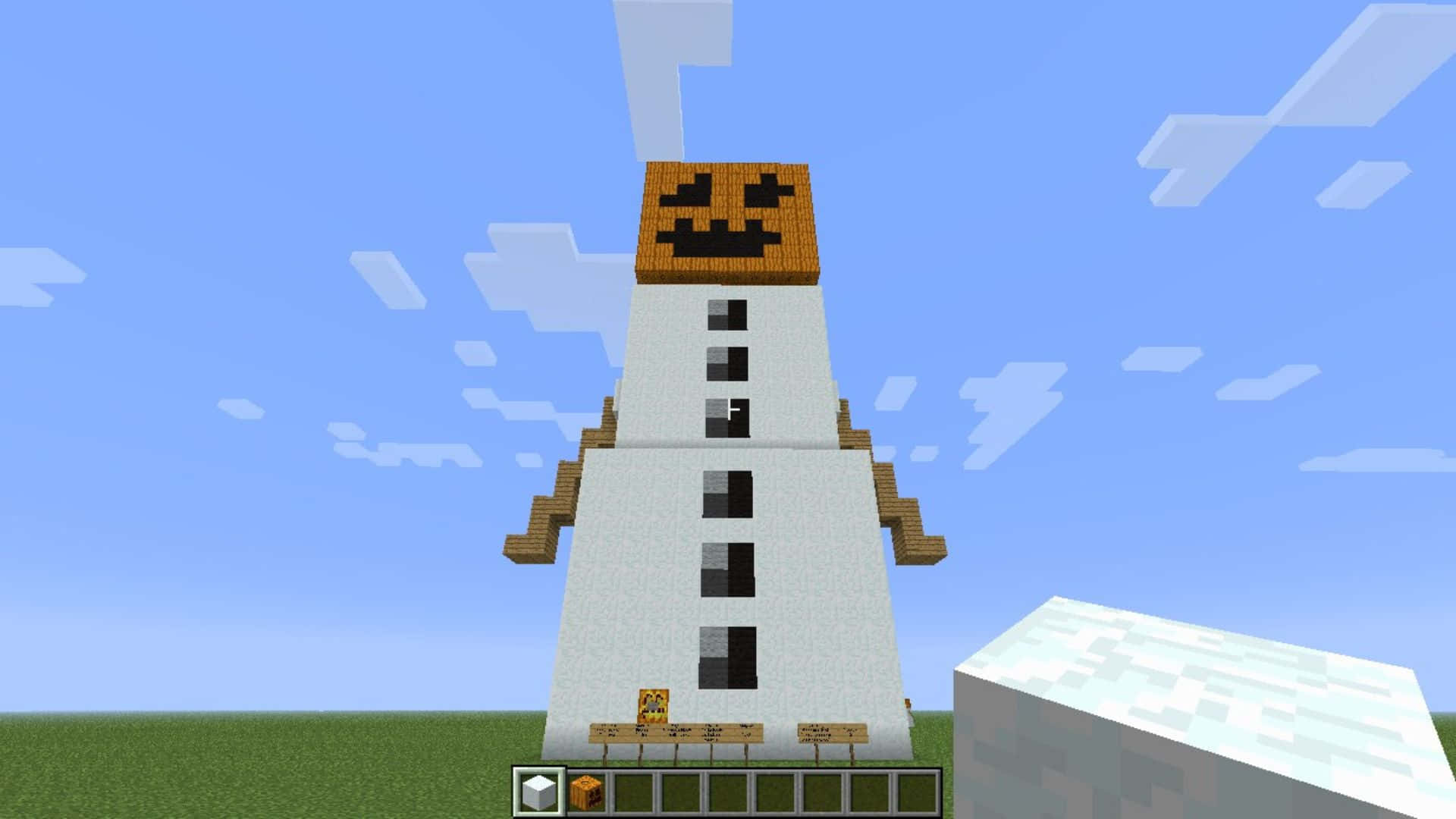 Minecraft Snow Golem 桌布 壁紙 — 一個高大的雪人，頭部是南瓜，站在草地上，背景是晴朗的藍天和方塊狀的雲朵。