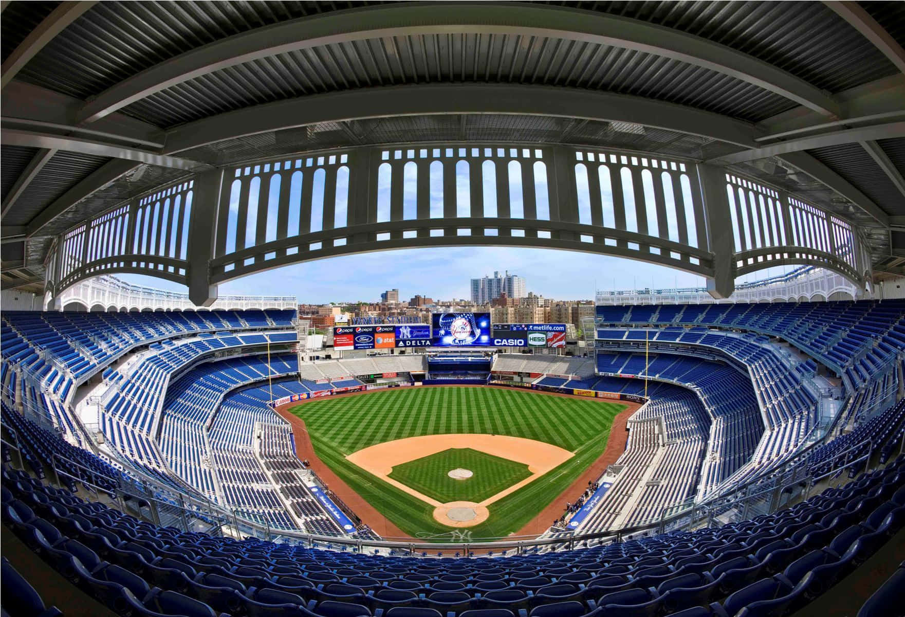 Baseball Stadium 桌布 壁紙 — 一個魚眼視角的棒球場，藍色座位和綠色場地，天空晴朗。