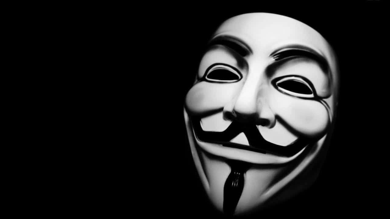 Anonymous 桌布 壁紙 — 一個鮮明的白色蓋伊·福克斯面具在漆黑背景上發光，帶有戲劇性的燈光效果。
