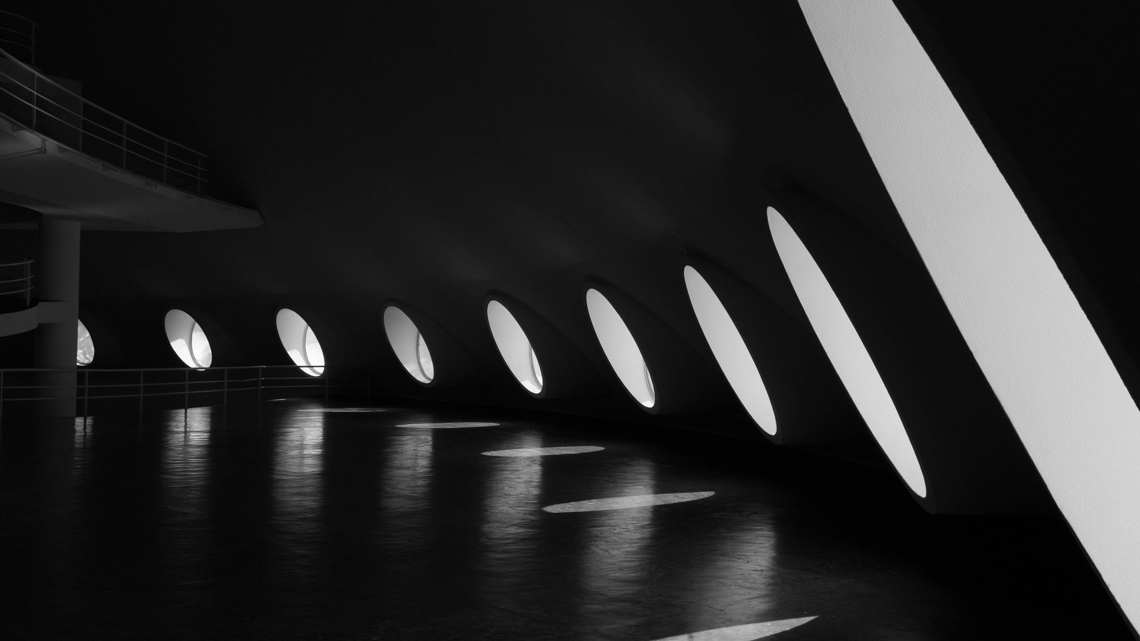 Interior Design 桌布 壁紙 — 一個鮮明的黑白建築室內設計，帶有彎曲的牆壁和圓形窗戶，在光澤地板上投射出明亮的倒影。