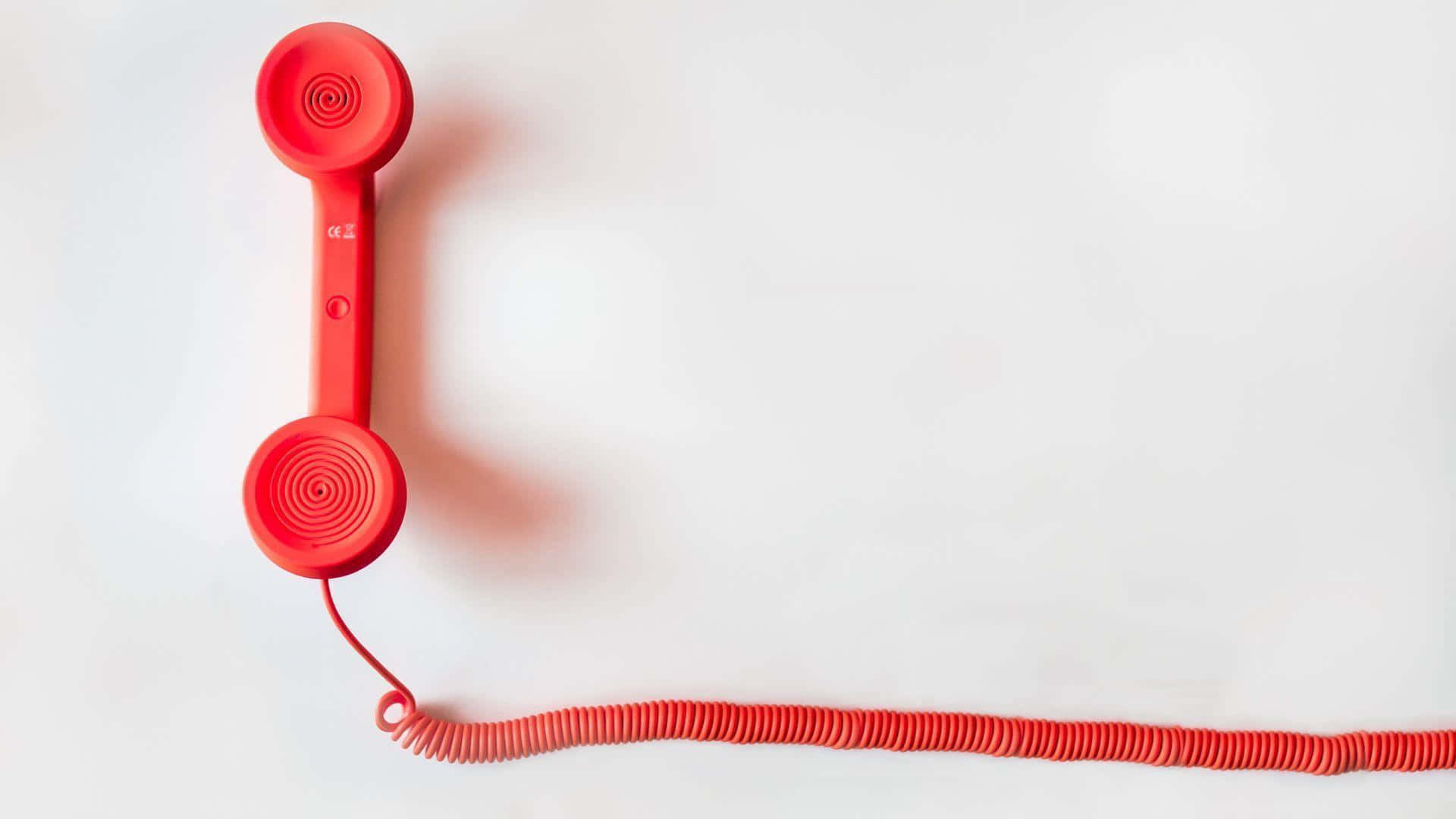 Phone Call 桌布 壁紙 — 一個鮮紅色復古電話聽筒放在純白色表面上，螺旋電線延伸出畫面。