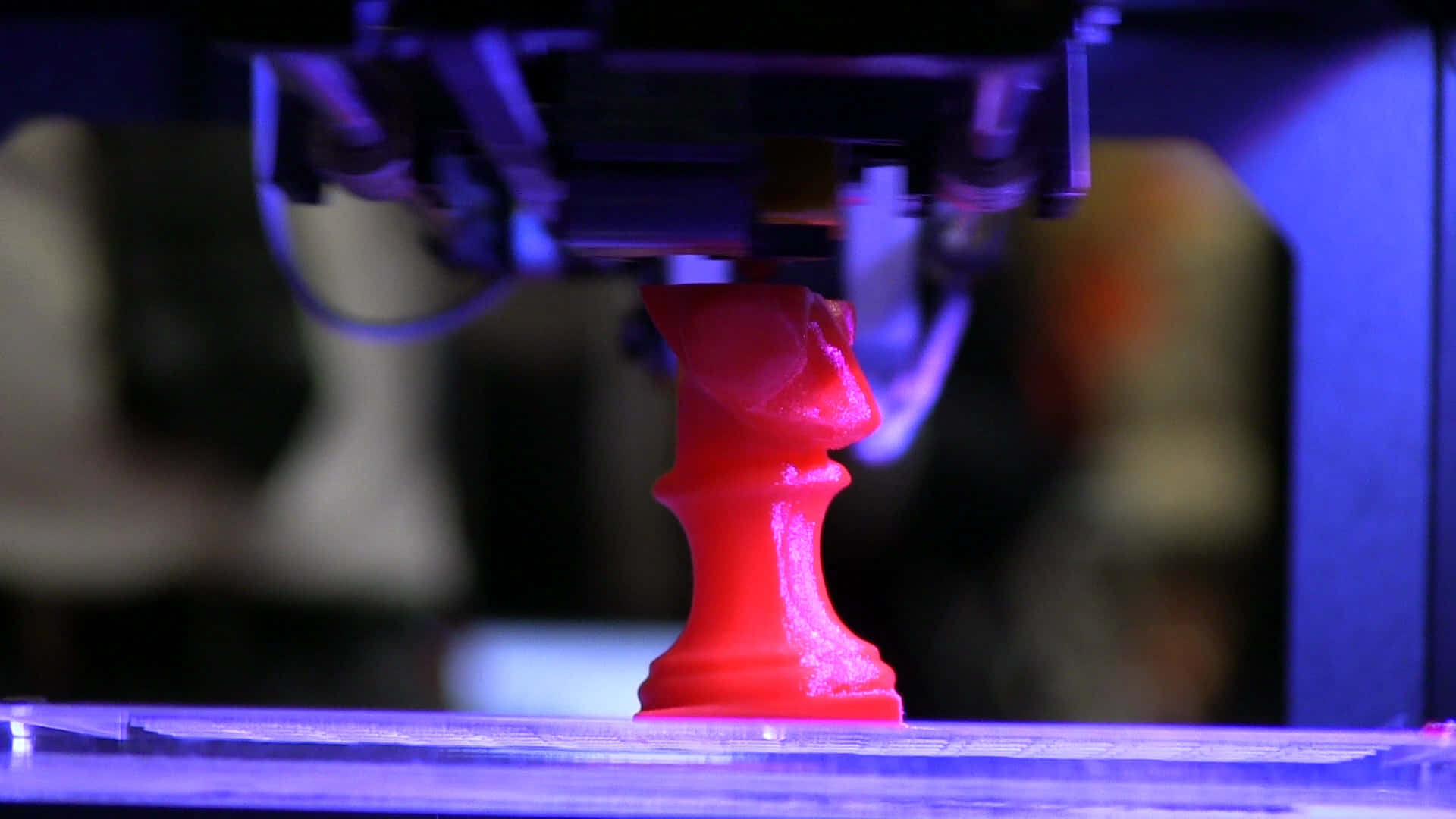 3d Printer 桌布 壁紙 — 一個鮮紅色的3D打印國際象棋棋子，在沐浴在冷藍光下的3D打印機噴嘴下方出現。
