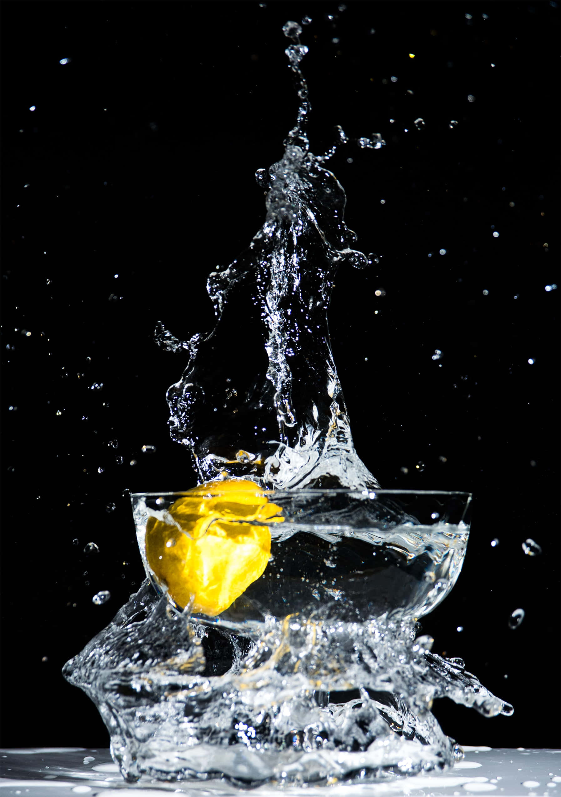 Hydration 桌布 壁紙 — 一個鮮黃色的檸檬掉進清澈的水中，在純黑背景上形成戲劇性的水花。