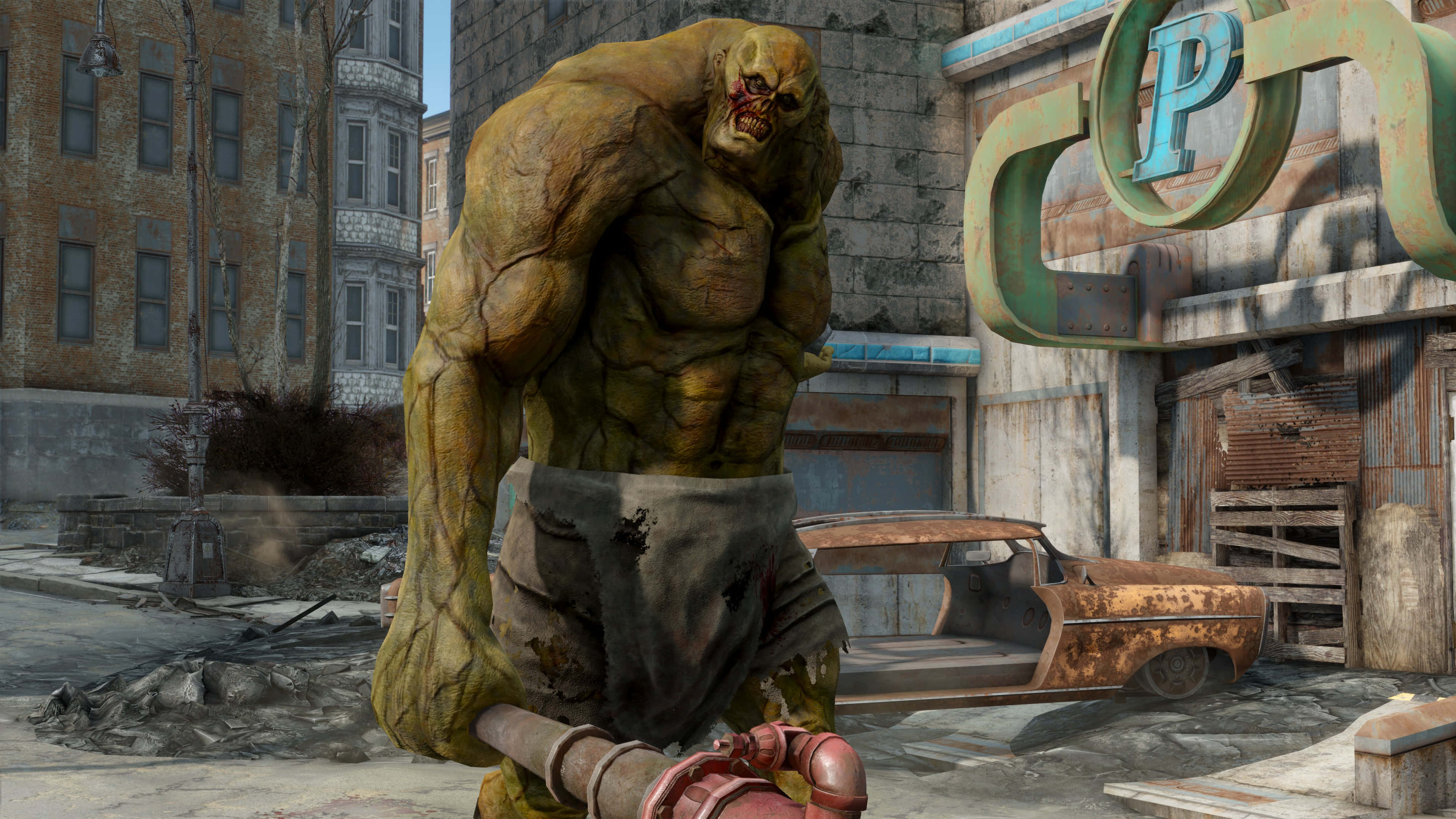 Fallout 4 The Capital Wasteland 桌布 壁紙 — 一個黃皮膚的怪異突變怪物威嚇地站在一條破敗的城市街道上，有一輛生鏽的汽車和搖搖欲墜的建築物。