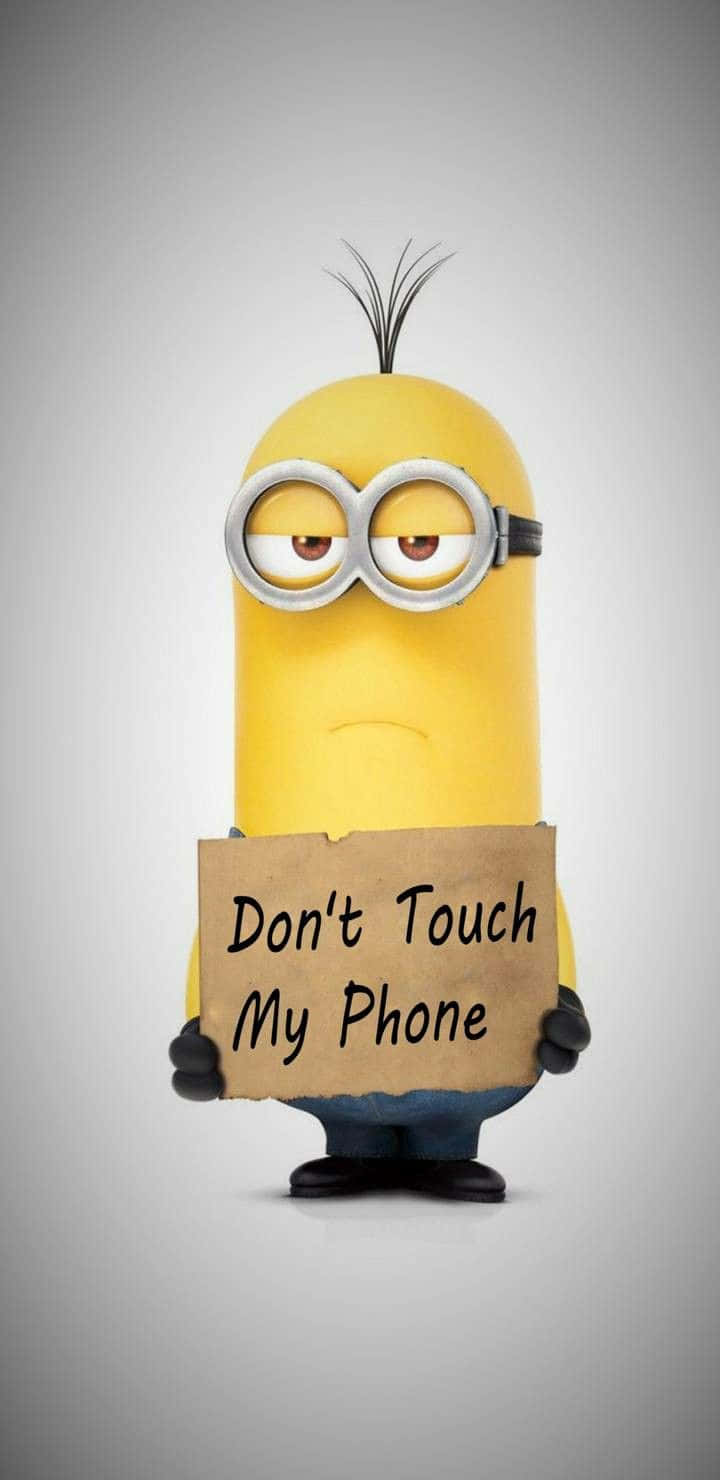 迷你兵團 桌布 壁紙 — 一個黃色Minion，有一束黑色頭髮和護目鏡，在灰色背景前舉著一個寫著「Don't Touch My Phone」的紙板標語。