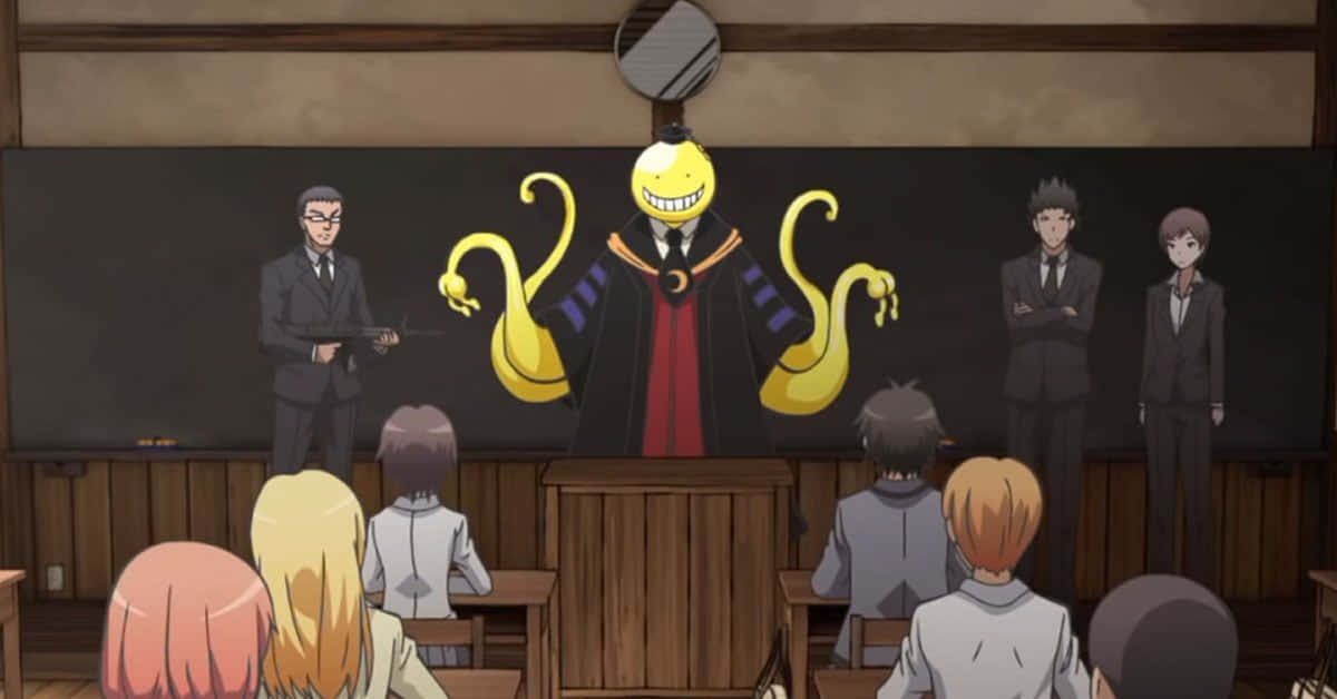 Koro Sensei 桌布 壁紙 — 一個黃色笑臉動漫角色，擁有蛇形手臂，站在教室前，學生和老師們都在觀看。