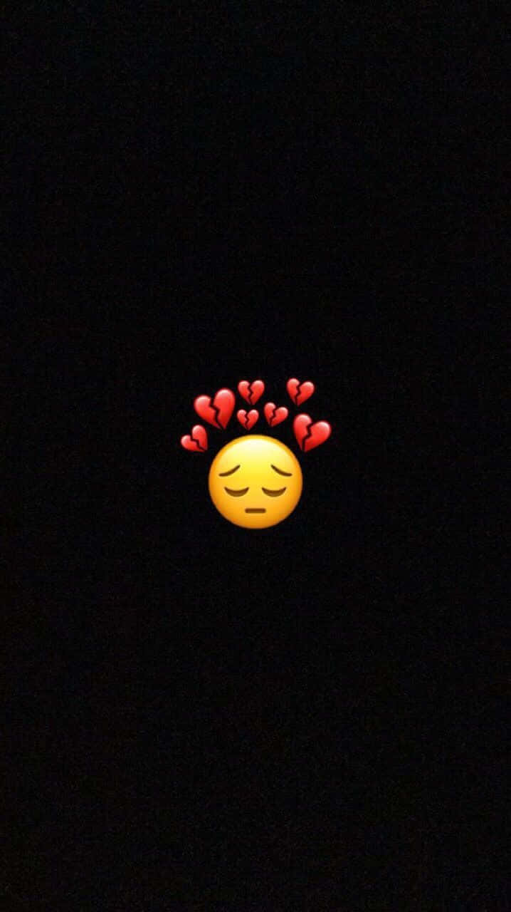 Broken Heart Black 桌布 壁紙 — 一個黃色表情符號，閉著眼睛，破碎的紅色心形漂浮在頭頂上方，背景為黑色。
