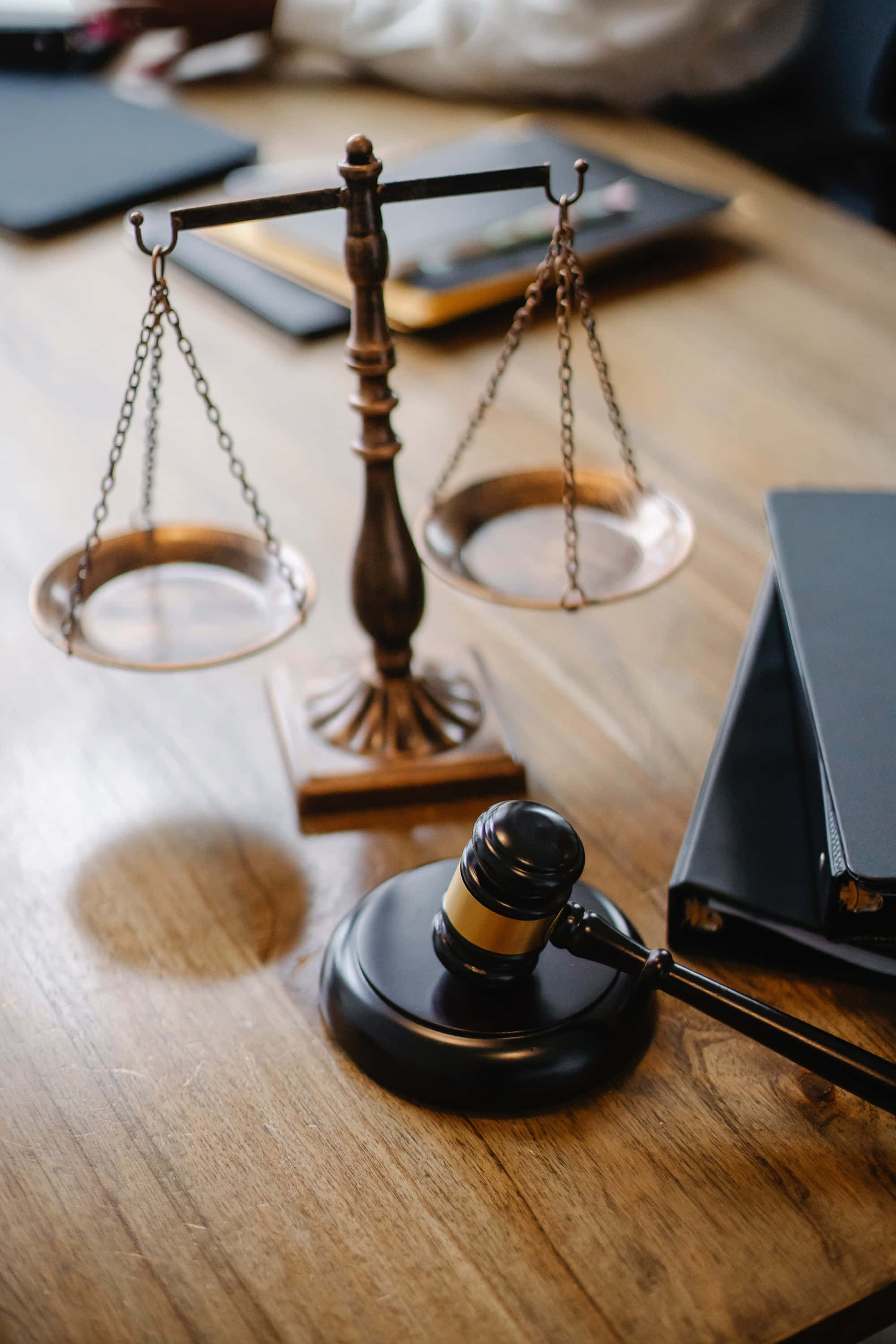 Law 桌布 壁紙 — 一個黃銅法律天秤和木槌放在木桌上，旁邊有黑色活頁夾和筆記本。