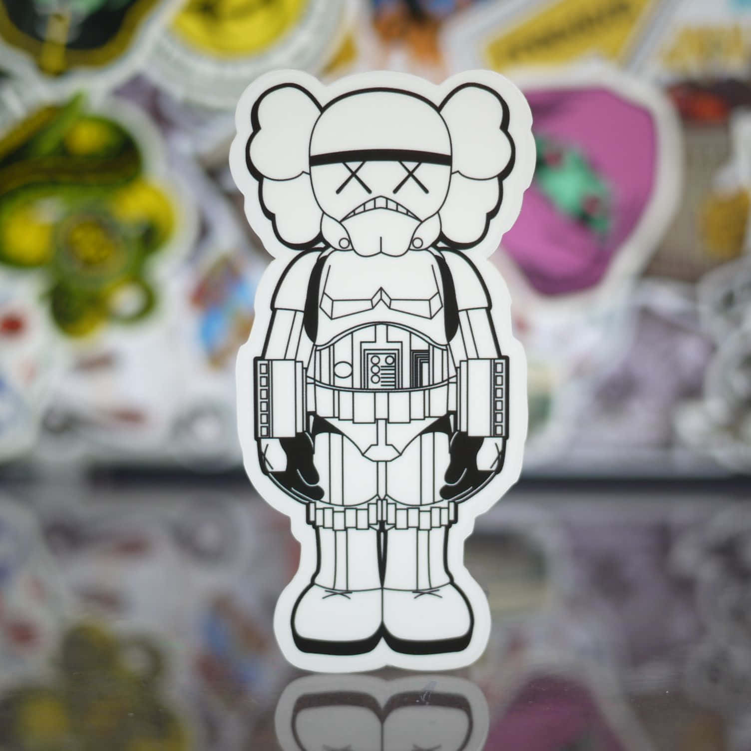 Kaws Stormtrooper 桌布 壁紙 — 一個黑白KAWS風暴兵貼紙在其他貼紙的彩色模糊背景中清晰對焦。