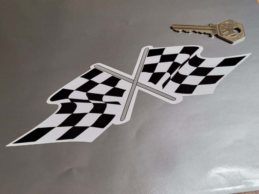 Chequered Flag 桌布 壁紙 — 一個黑白格仔賽車旗翼形貼紙放在銀色表面上的一個金屬鑰匙旁邊。
