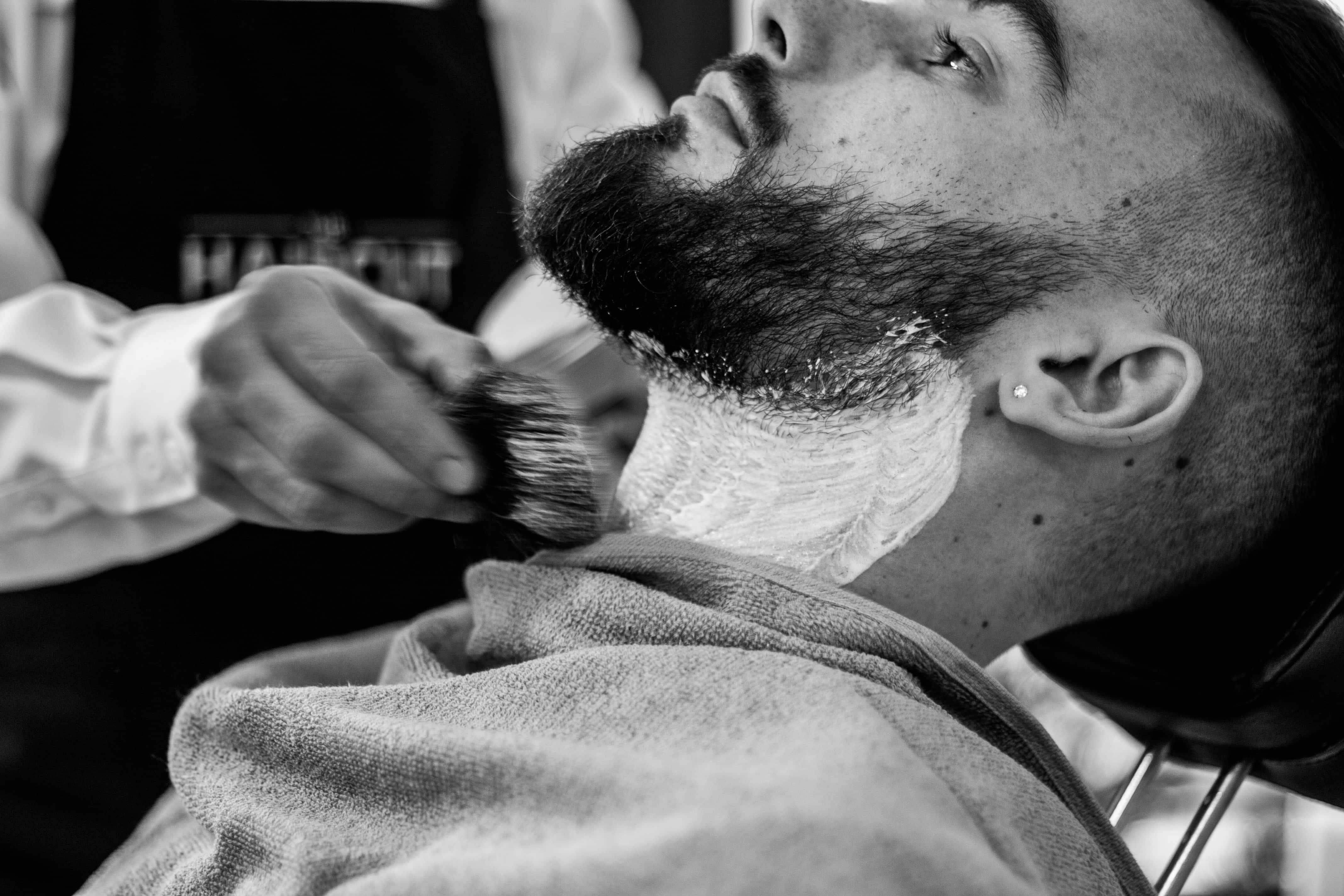 Barber 桌布 壁紙 — 一個黑白特寫，一名男子躺在理髮椅上，用刷子修剪鬍鬚。