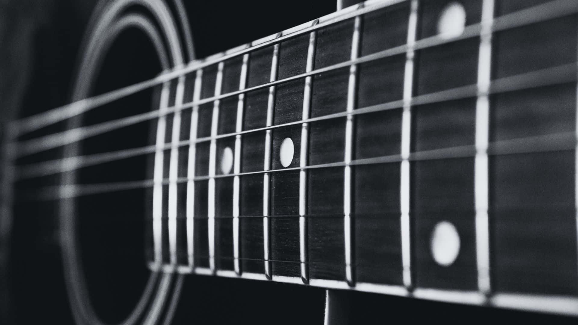 Black And White Guitar 桌布 壁紙 — 一個黑白特寫，聚焦於木結他的指板，弦線和鑲嵌在深色背景下清晰可見。