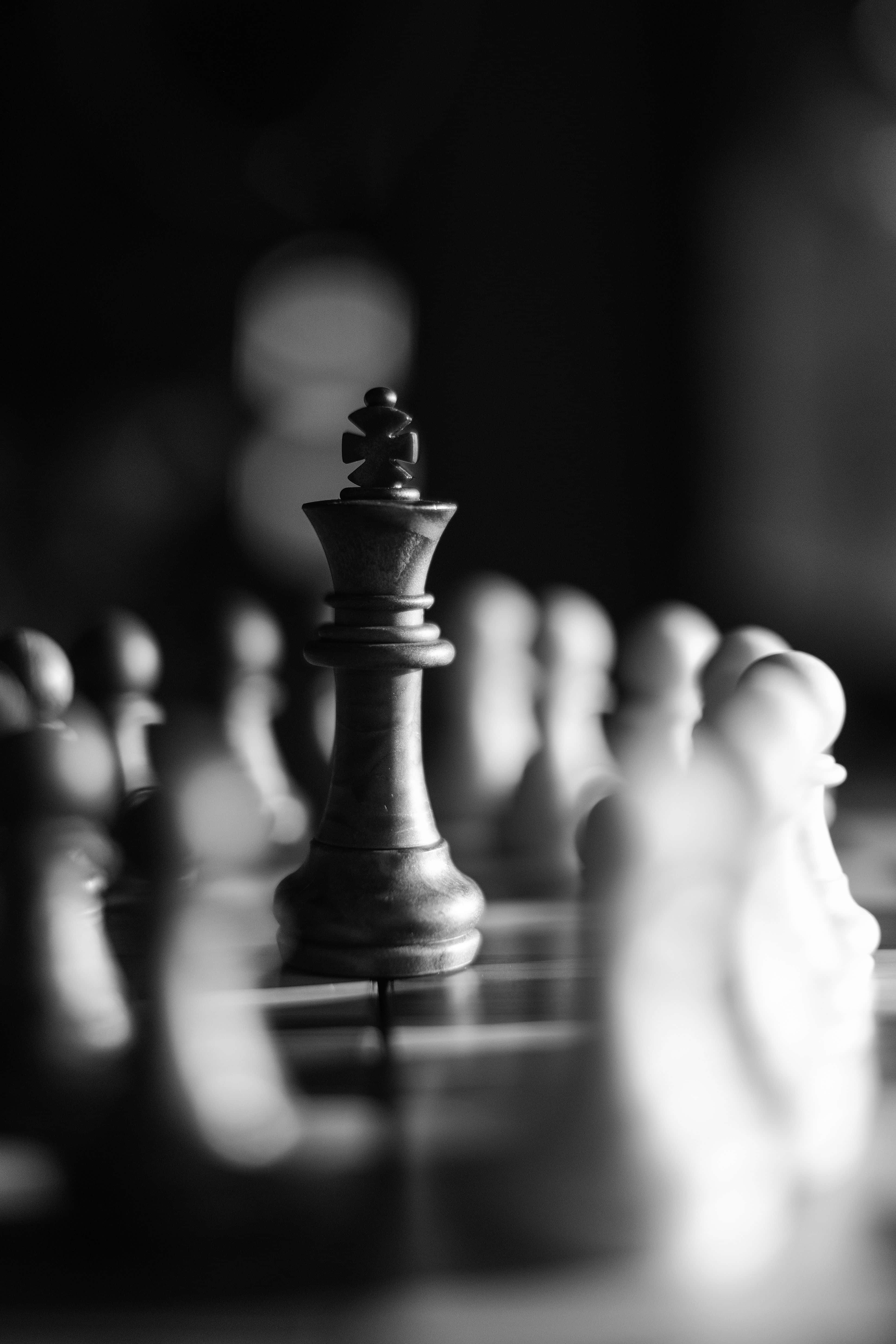 Black And White Chess 桌布 壁紙 — 一個黑白特寫，顯示一枚國際象棋國王棋子高高立在棋盤上，背景有模糊的對手棋子。