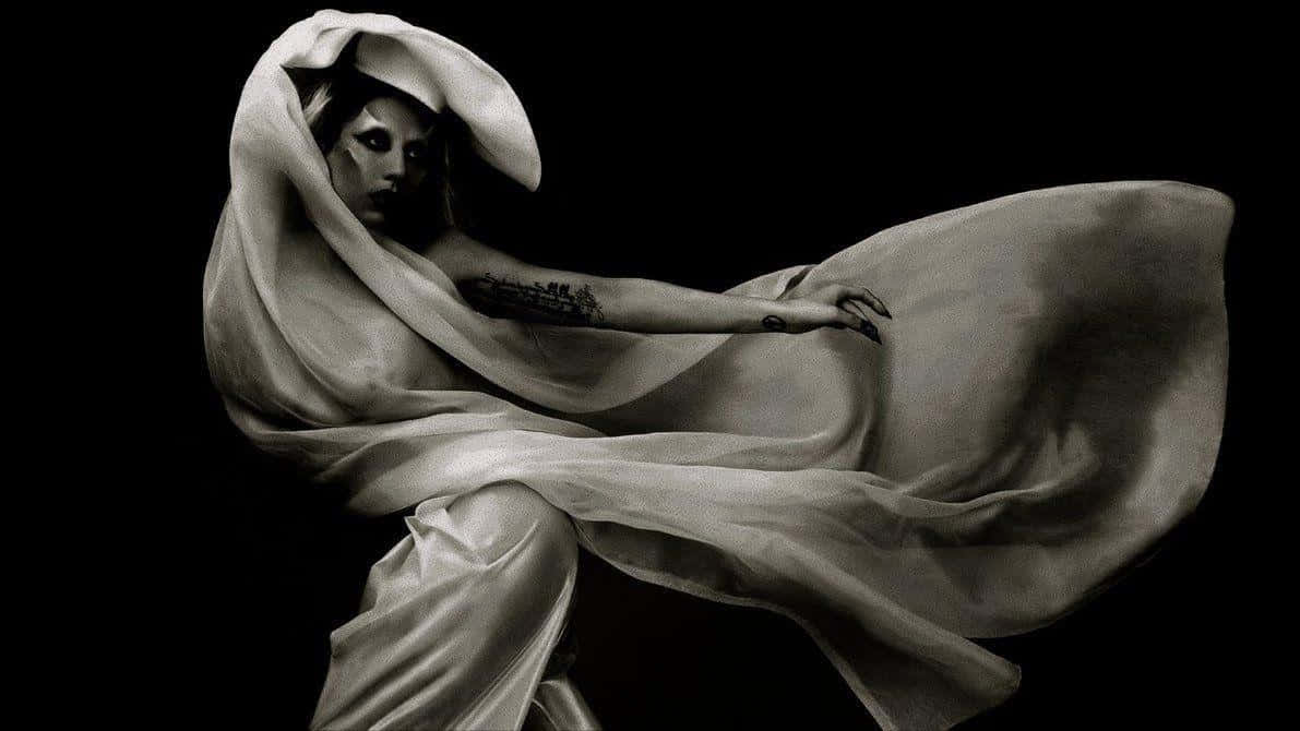 Lady Gaga 桌布 壁紙 — 一個黑白肖像，一位女士披著飄逸布料，背景是純黑色。
