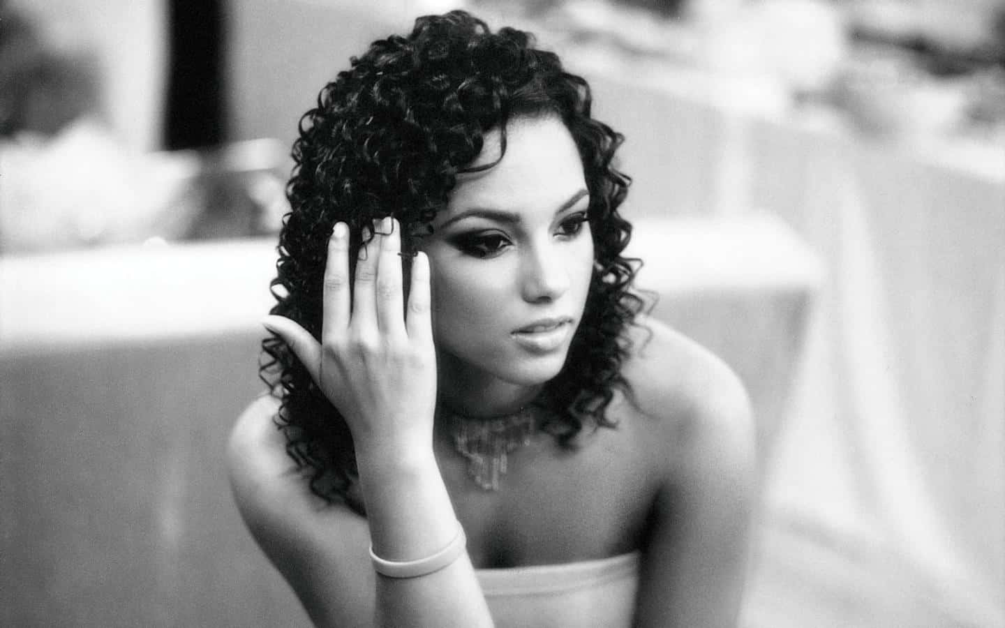 Alicia Keys 桌布 壁紙 — 一個黑白肖像，一位捲髮女性以沉思姿態輕輕觸摸臉龐。