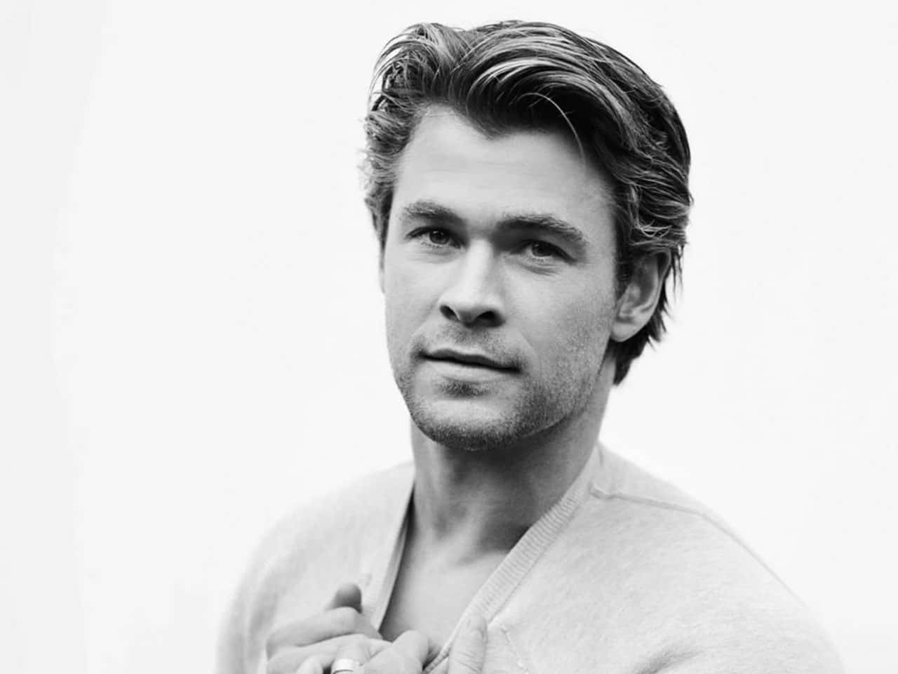 Black And White Celebrity 桌布 壁紙 — 一個黑白肖像，一名男子梳著時尚髮型，穿著淺色毛衣，背景簡潔。