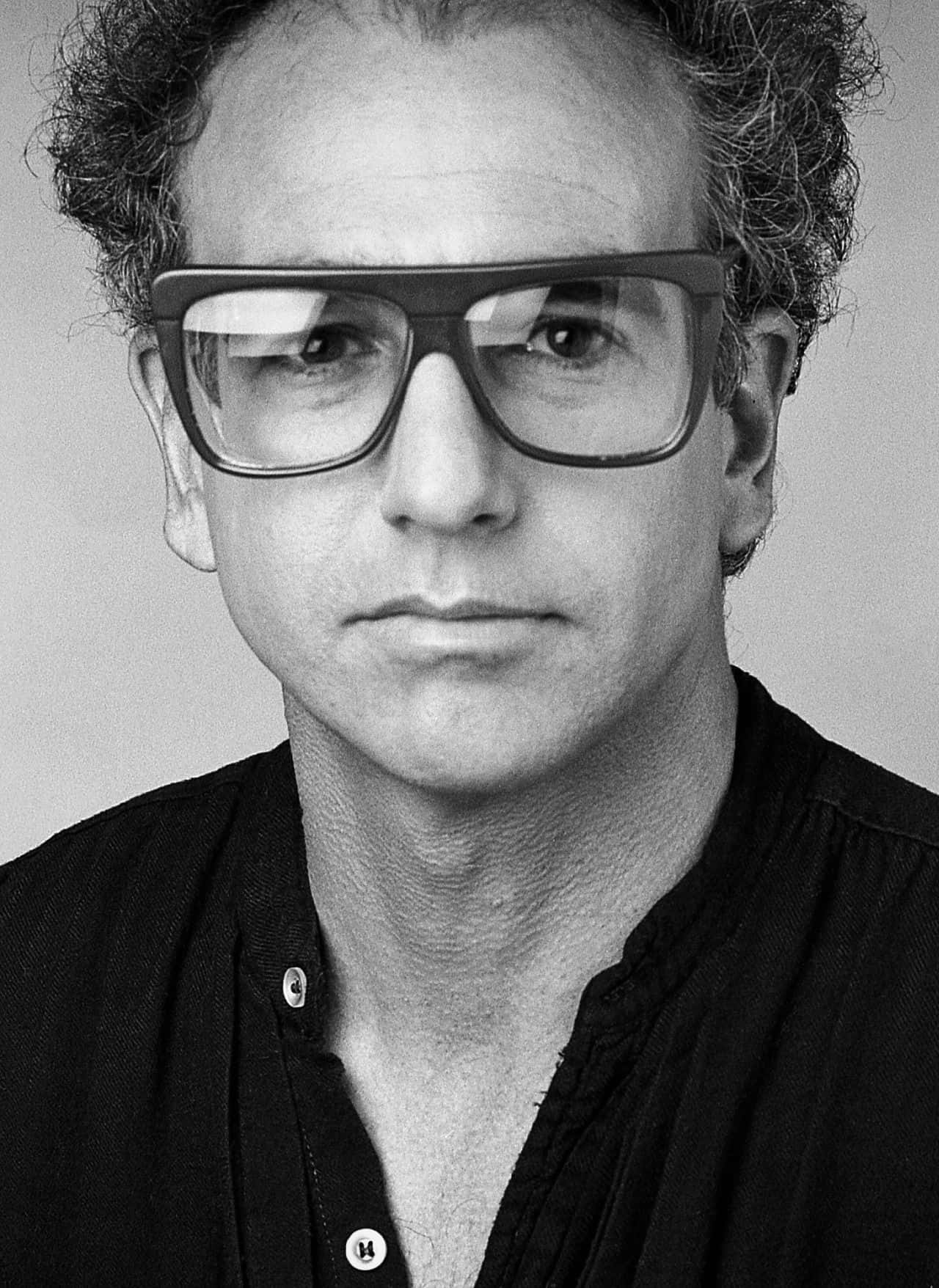 larry david 桌布 壁紙 — 一個黑白肖像，拍攝一名蓄有曲髮、戴粗框眼鏡的男子直視鏡頭。