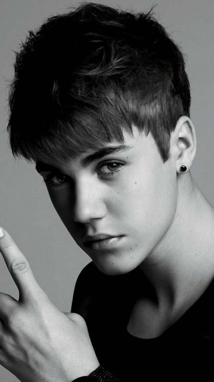 Justin Bieber 桌布 壁紙 — 一個黑白肖像，描繪一位頭髮蓬鬆、戴著耳環的年輕男子做出手勢。