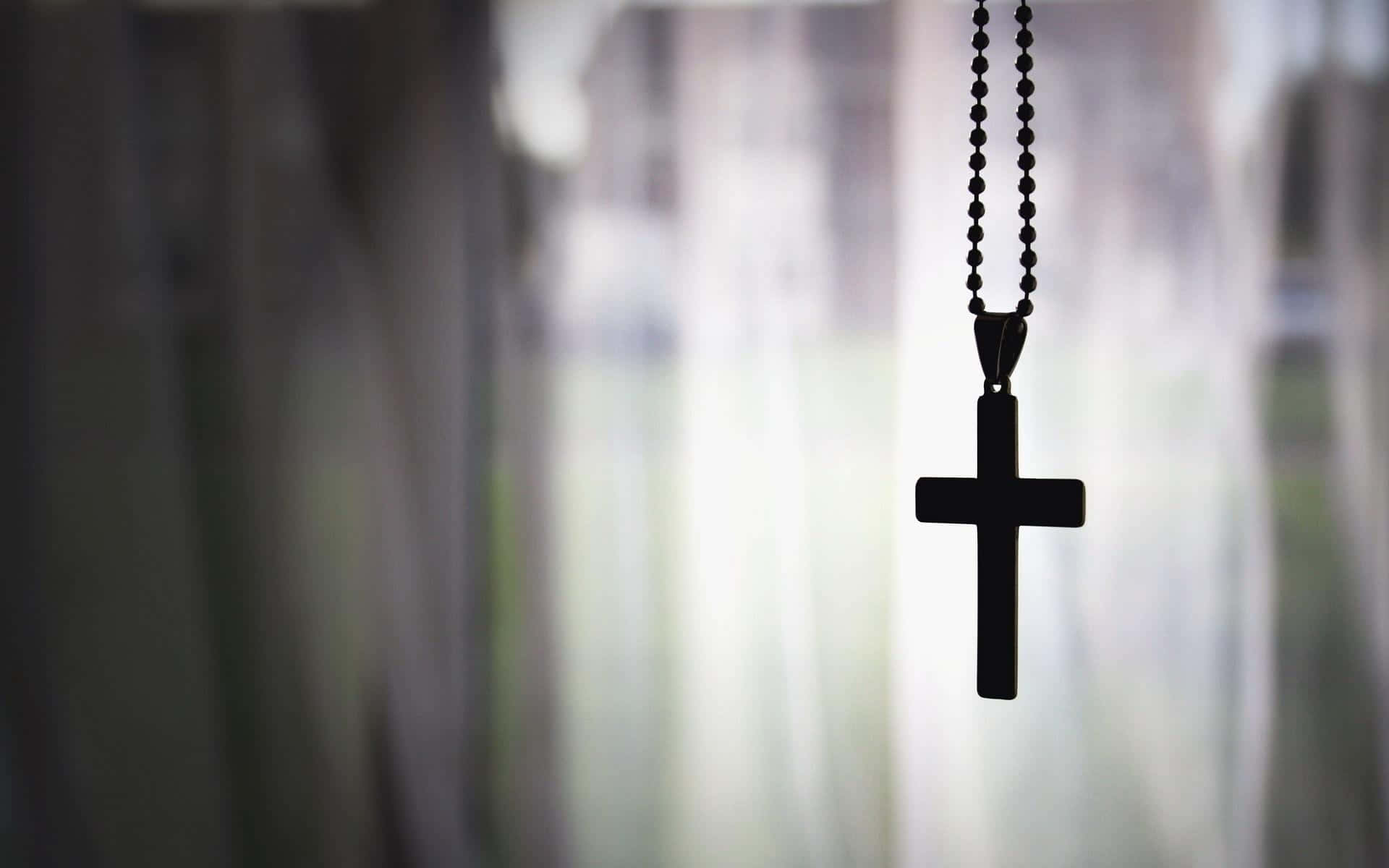 Faith 桌布 壁紙 — 一個黑色十字架吊墜在柔和模糊的窗戶和漫射日光中呈現剪影。