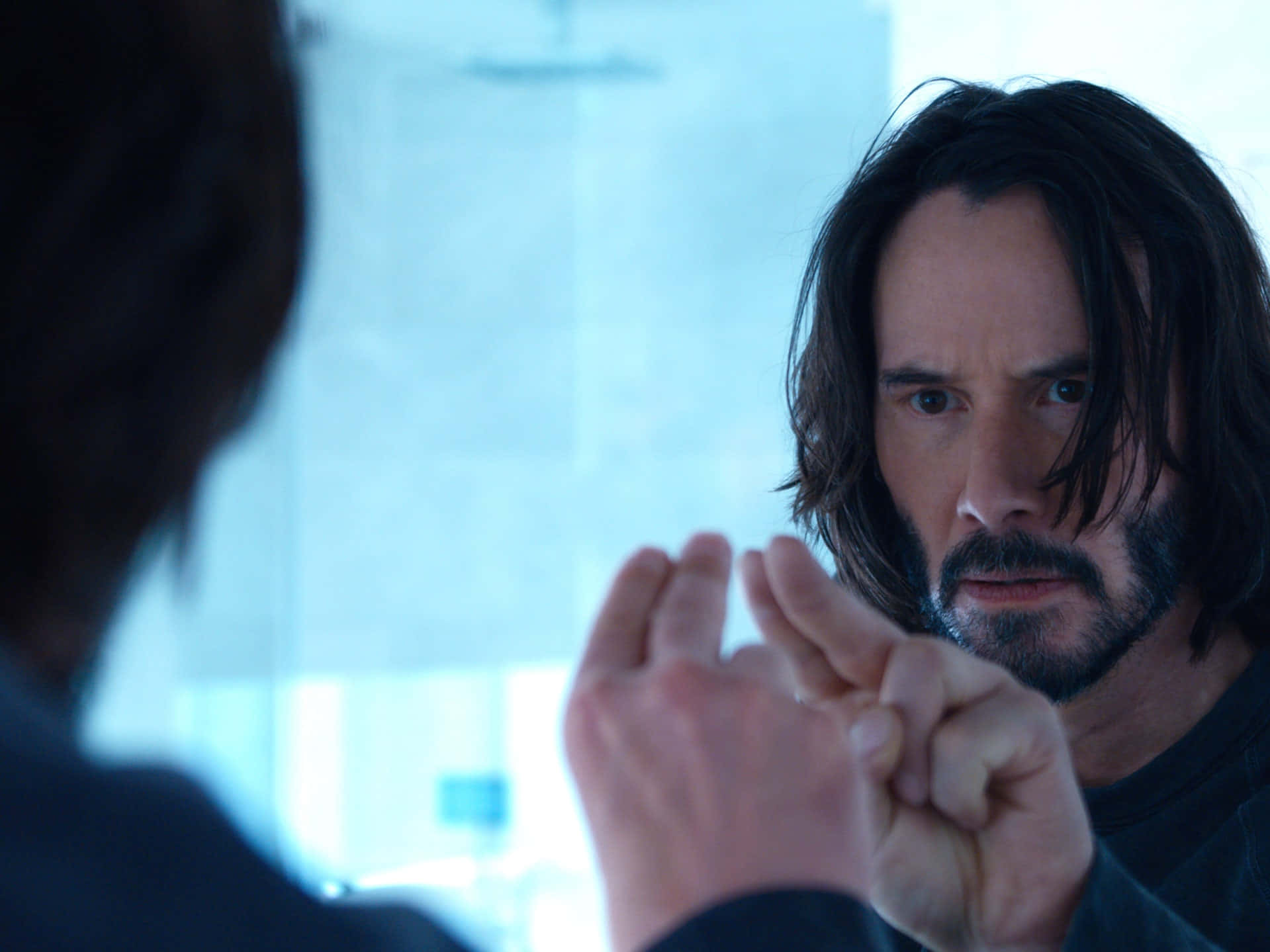 Keanu Reeves 桌布 壁紙 — 一個黑髮留鬚的男人，一邊做手勢，一邊專注地凝視鏡中的倒影。