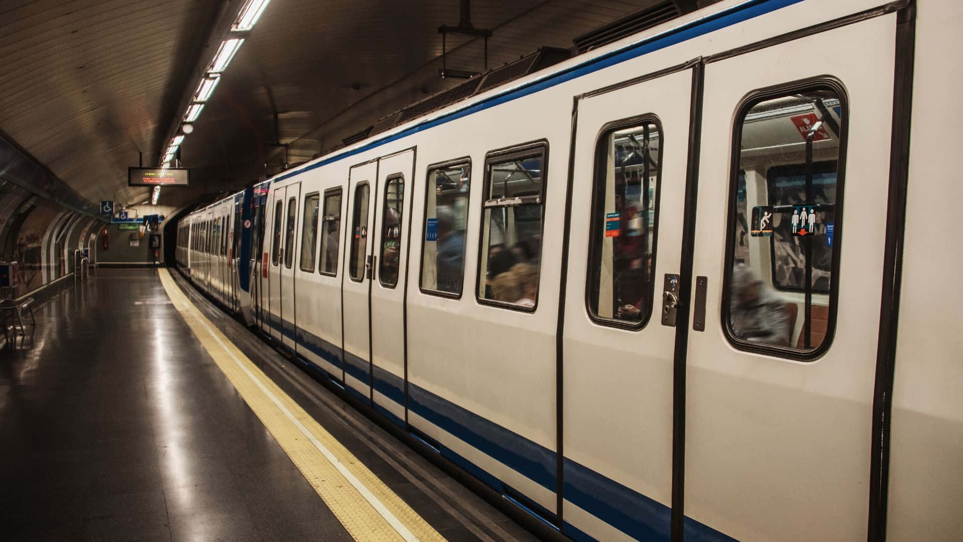 Subway 桌布 壁紙 — 一列時尚的白色和藍色地鐵列車停靠在光線昏暗的地下車站月台上，地板反光，頭頂有燈光。